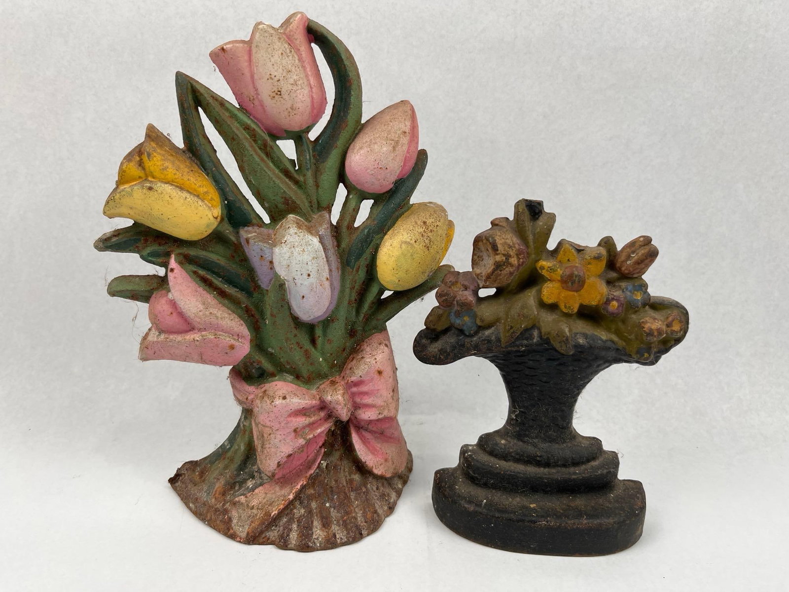 Pair Painted Floral Cast Iron Doorstops: Two vintage cast iron doorstops featuring floral motifs. The lot includes a Taiwanese polychrome painted tulip bouquet tied with a pink bow, featuring blossoms in shades of pink, yellow, and