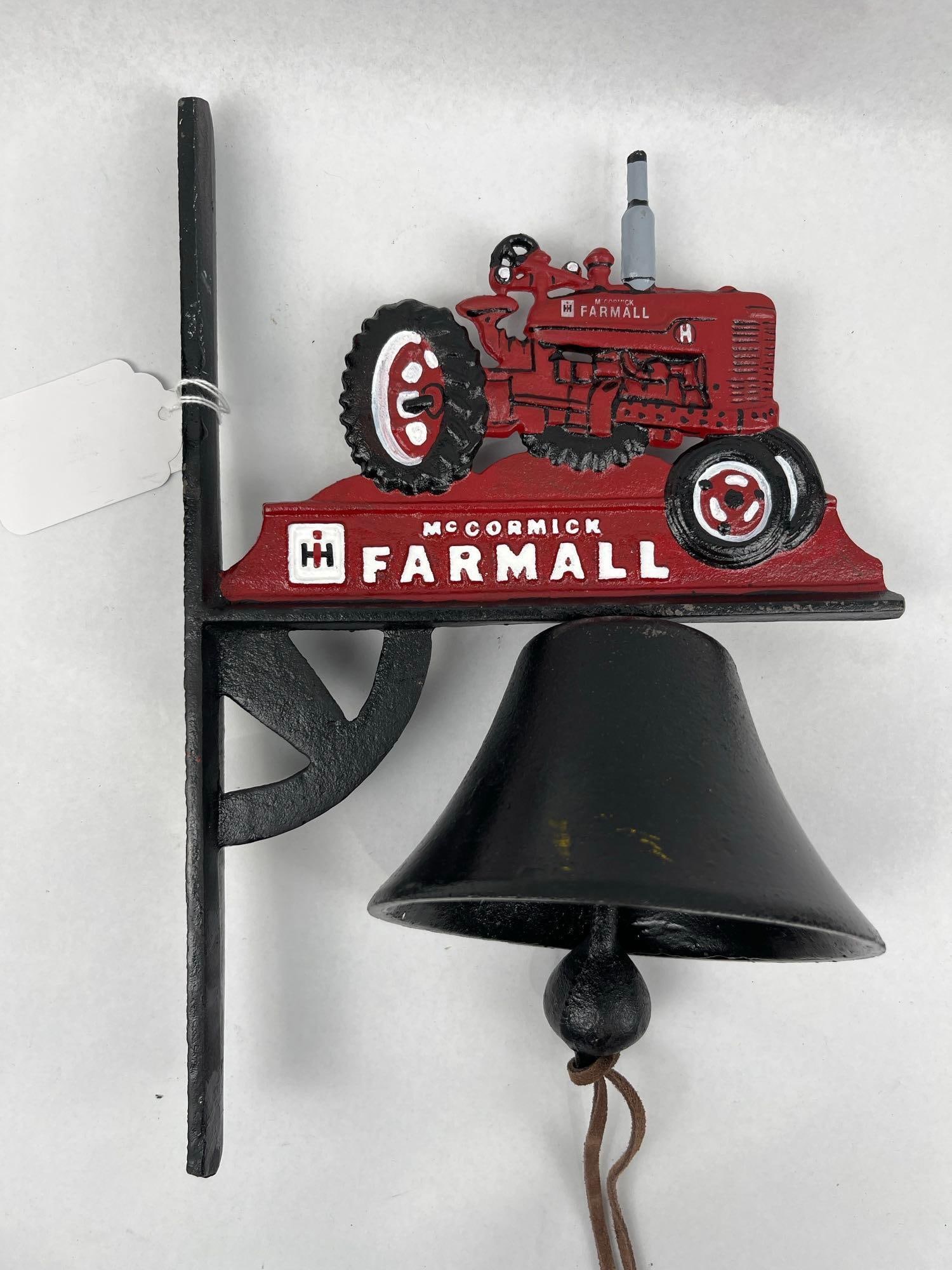 McCormick Farmall Tractor Dinner Bell: This wall-mounted dinner bell is constructed of cast iron and features a painted relief plaque depicting a red Farmall tractor. The two-sided plaque is positioned atop a base that displays a raised