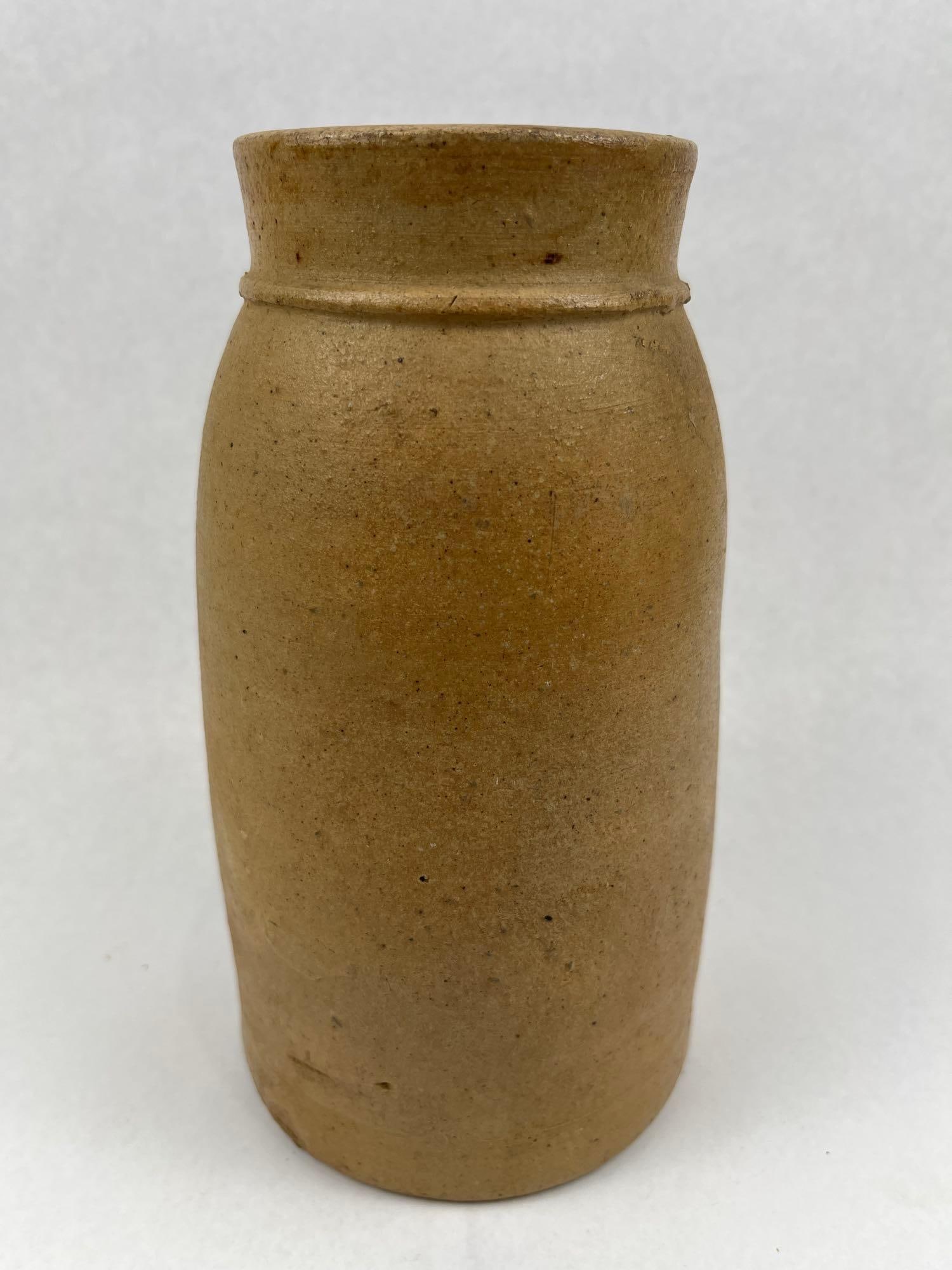 19th C. American Salt Stoneware Jar: A utilitarian 19th century American stoneware preserving jar of cylindrical form. The vessel features a slightly tapered base, rounded shoulders, and a flaring rim accented by a single raised rib at
