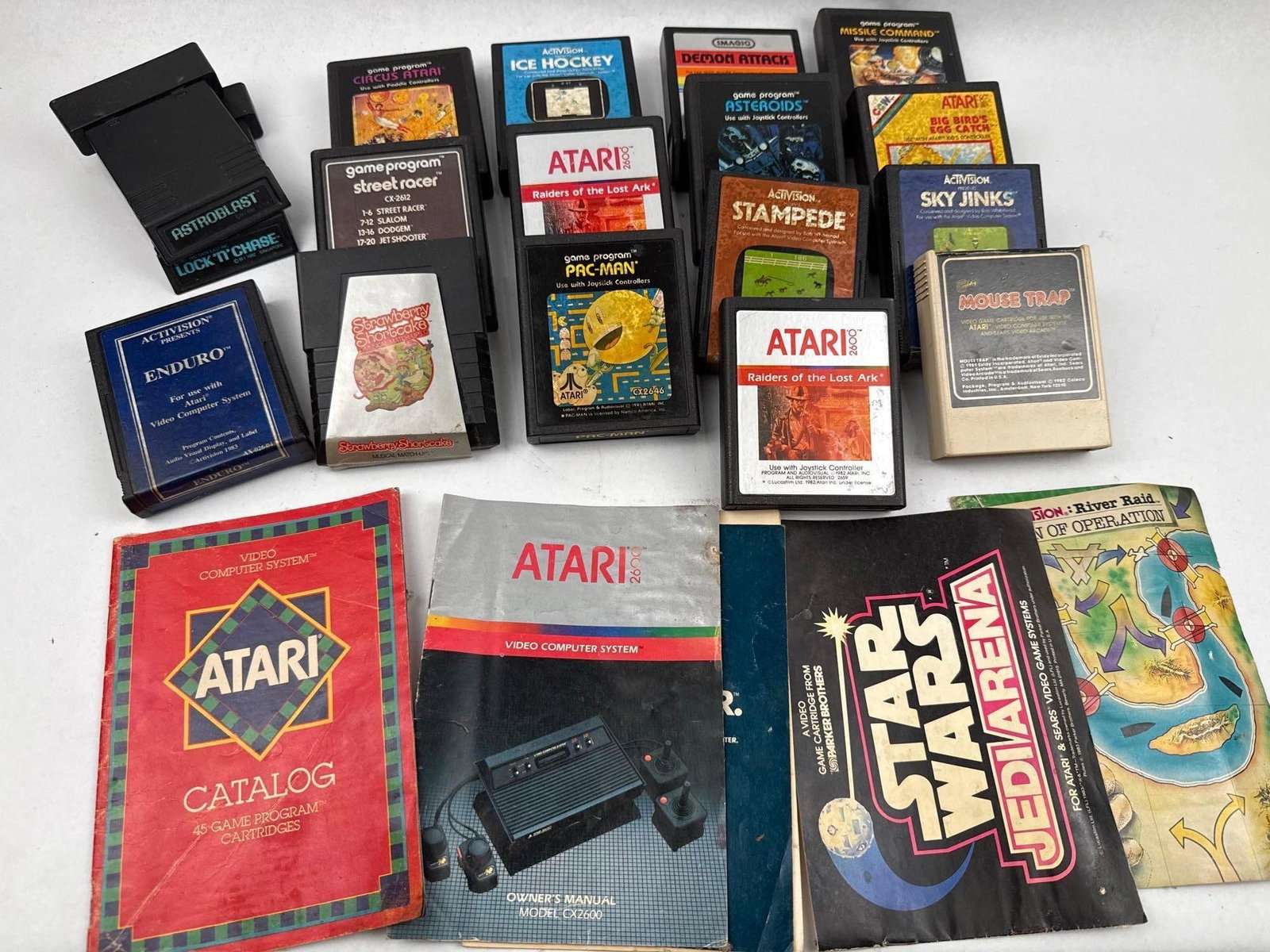 Atari 2600 Game Cartridges & Manuals: A group of vintage Atari 2600 video game cartridges and related instructional materials. The collection features cartridges from multiple publishers including Atari, Activision, Imagic, Coleco,