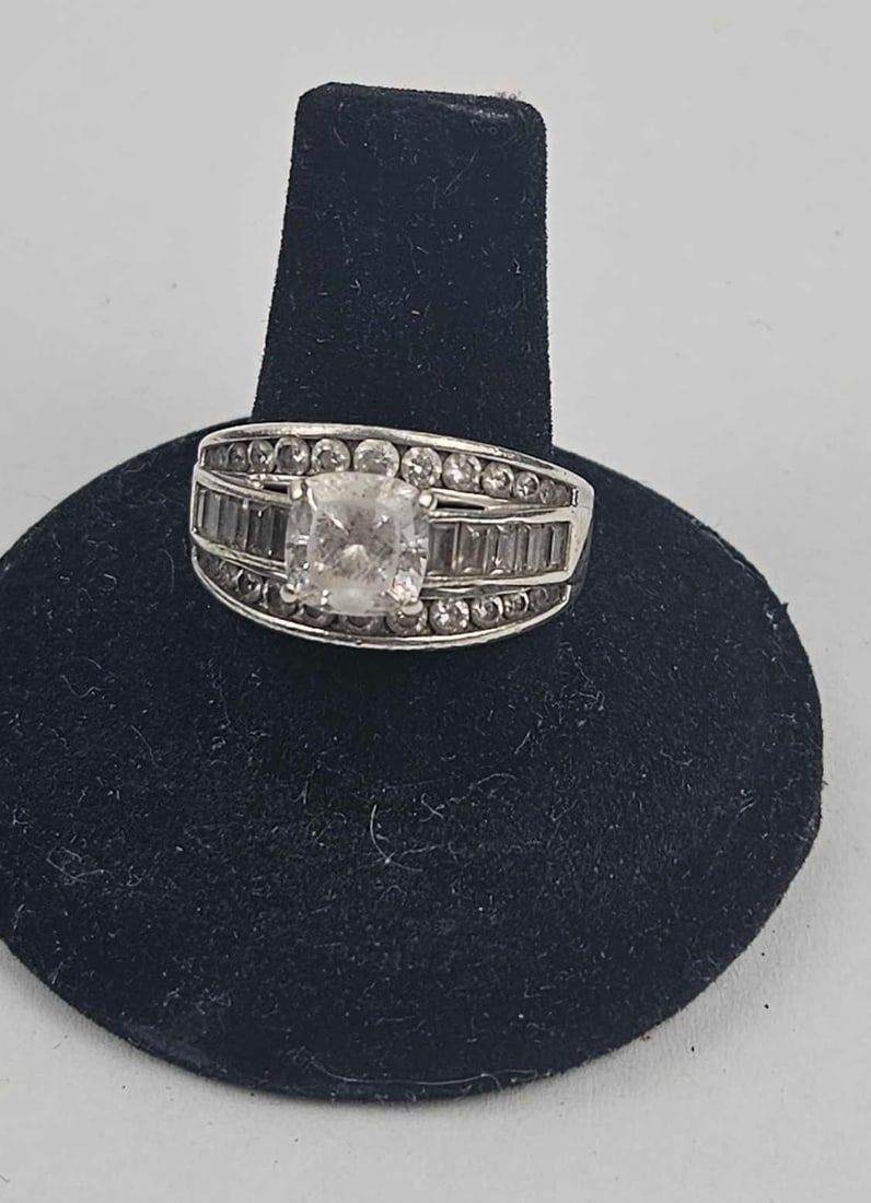 Str. Silver Cubic Zirconia Cluster Ring: This wide sterling silver ring features a multi-row cluster design. The head is set with a central prong-set cushion-cut colourless stone. This is flanked on either side by four parallel rows of