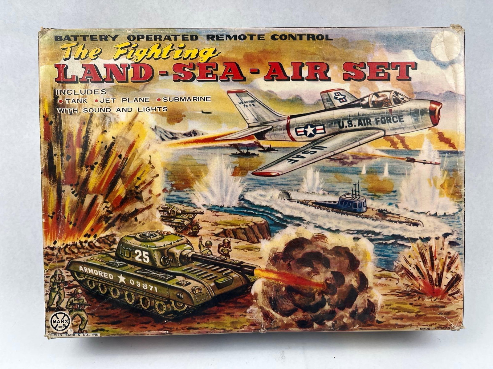 Marx Japanese Fighting Land-Sea-Air Set: A Japanese lithographed tin The Fighting Land-Sea-Air Set by Louis Marx & Co., Inc. includes a green camouflage tank, a silver jet plane, and a dark blue submarine. The original cardboard packaging