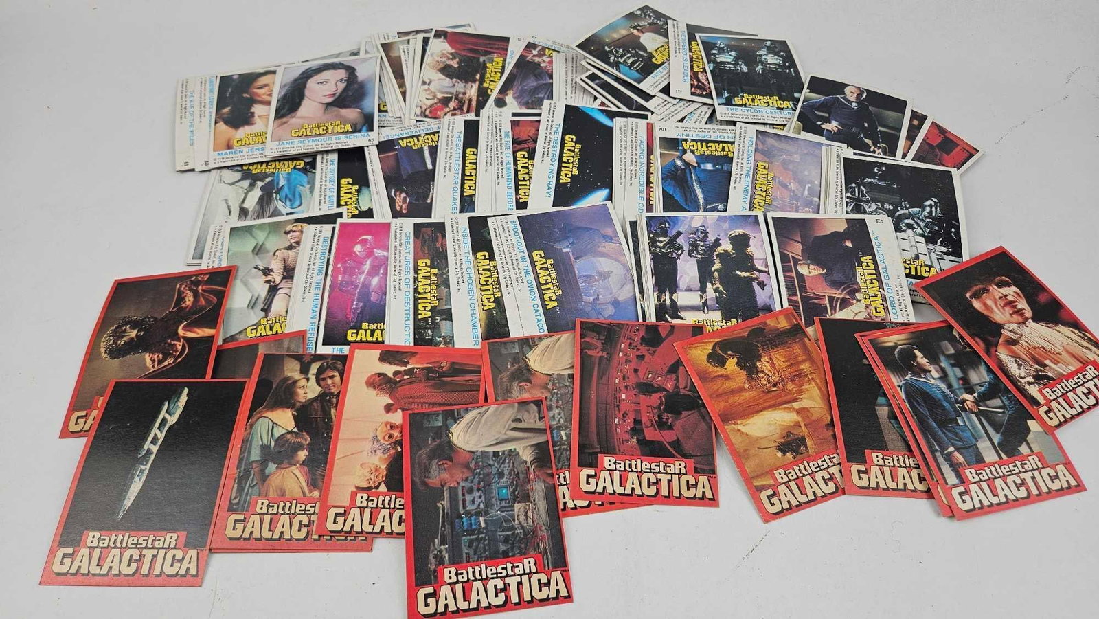 1978 Battlestar Galactica Trading Cards: A collection of printed cardstock trading cards and adhesive-backed paper stickers featuring imagery from the television series Battlestar Galactica. Each item is marked with the "BattlestaR GALACTICA