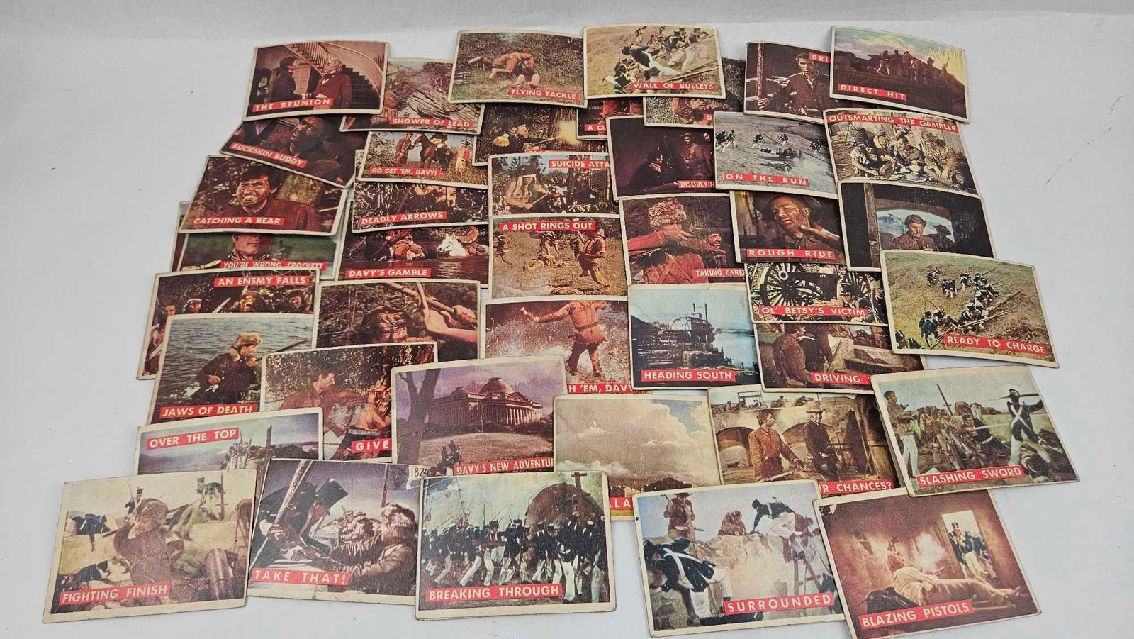 T.C.G. Davy Crockett Green Back Cards: An assortment of vintage mid-20th-century color lithographic trading cards featuring scenes from the Walt Disney film Davy Crockett, King of the Wild Frontier, starring Fess Parker. The fronts of the