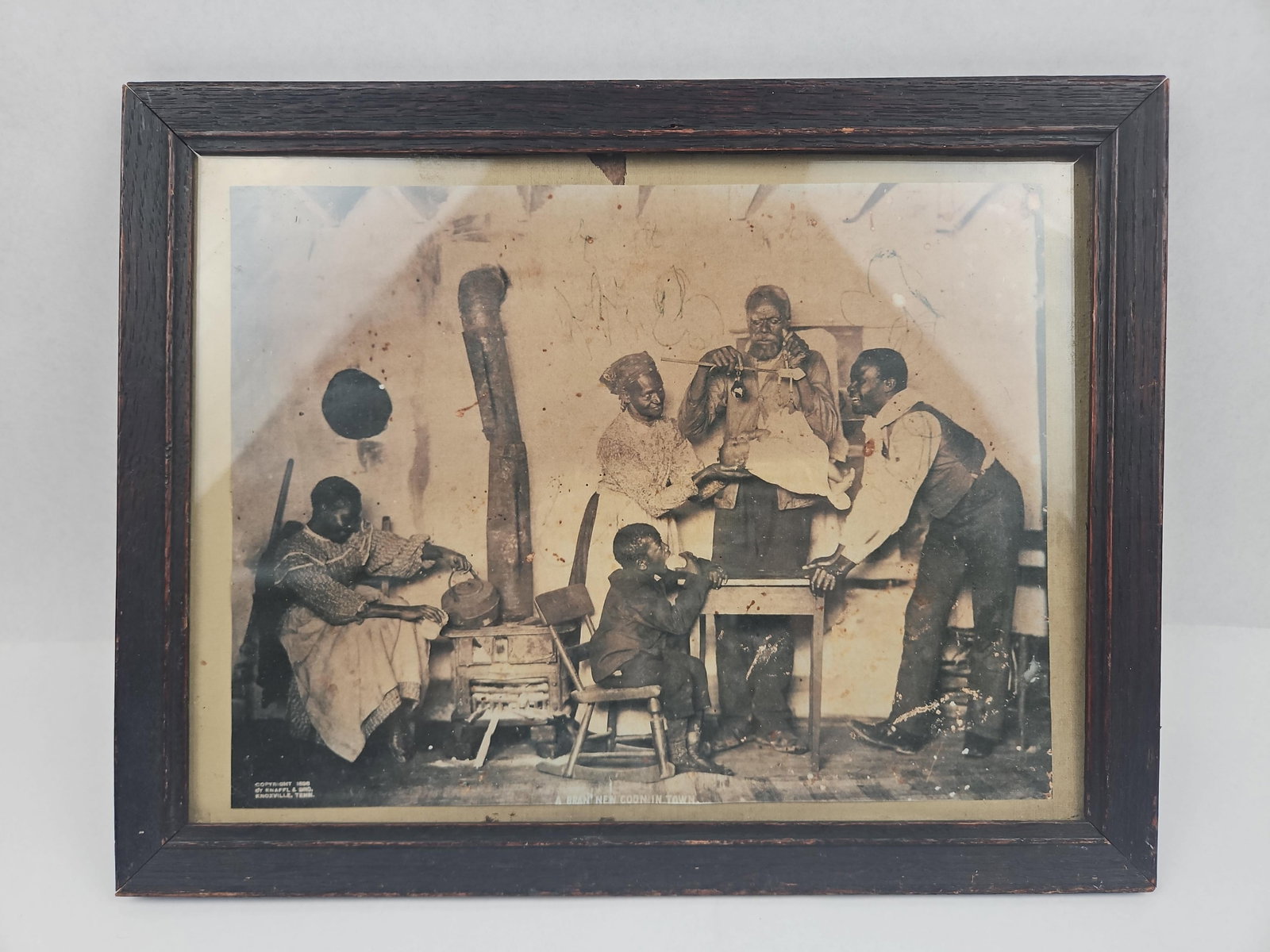 Knaffl & Bro. Family Scene Photo, 1898: A late 19th-century framed black-and-white photograph by Knaffl & Bro. of Knoxville, Tennessee, depicting a staged domestic interior scene with several African American subjects. A man holds a hand
