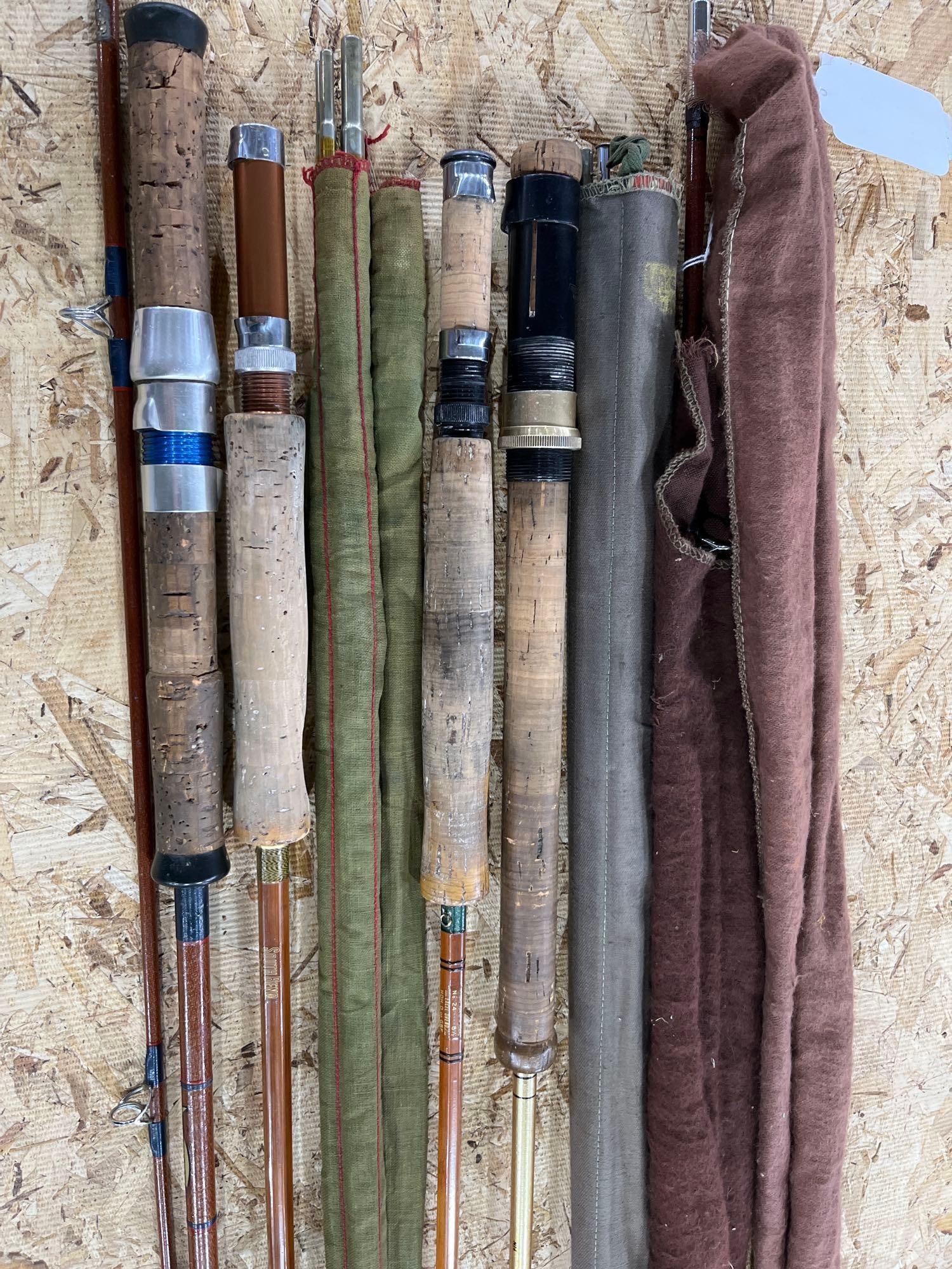 South Bend & Garcia Conolon Rods: A collection of vintage split bamboo and fiberglass fishing rods accompanied by several cloth storage sleeves. The group includes a split bamboo fly rod featuring a gold-toned inscription reading