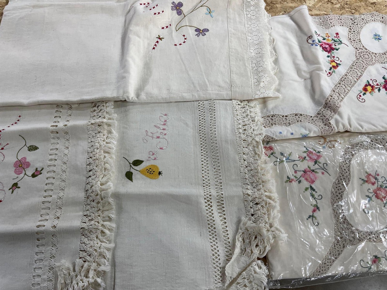 Chinese Crochet & Embroidered Textiles: An assortment of Chinese white cotton household textiles featuring extensive hand-worked detailing. The collection includes tablecloths and smaller linens decorated with multi-colored cross-stitch