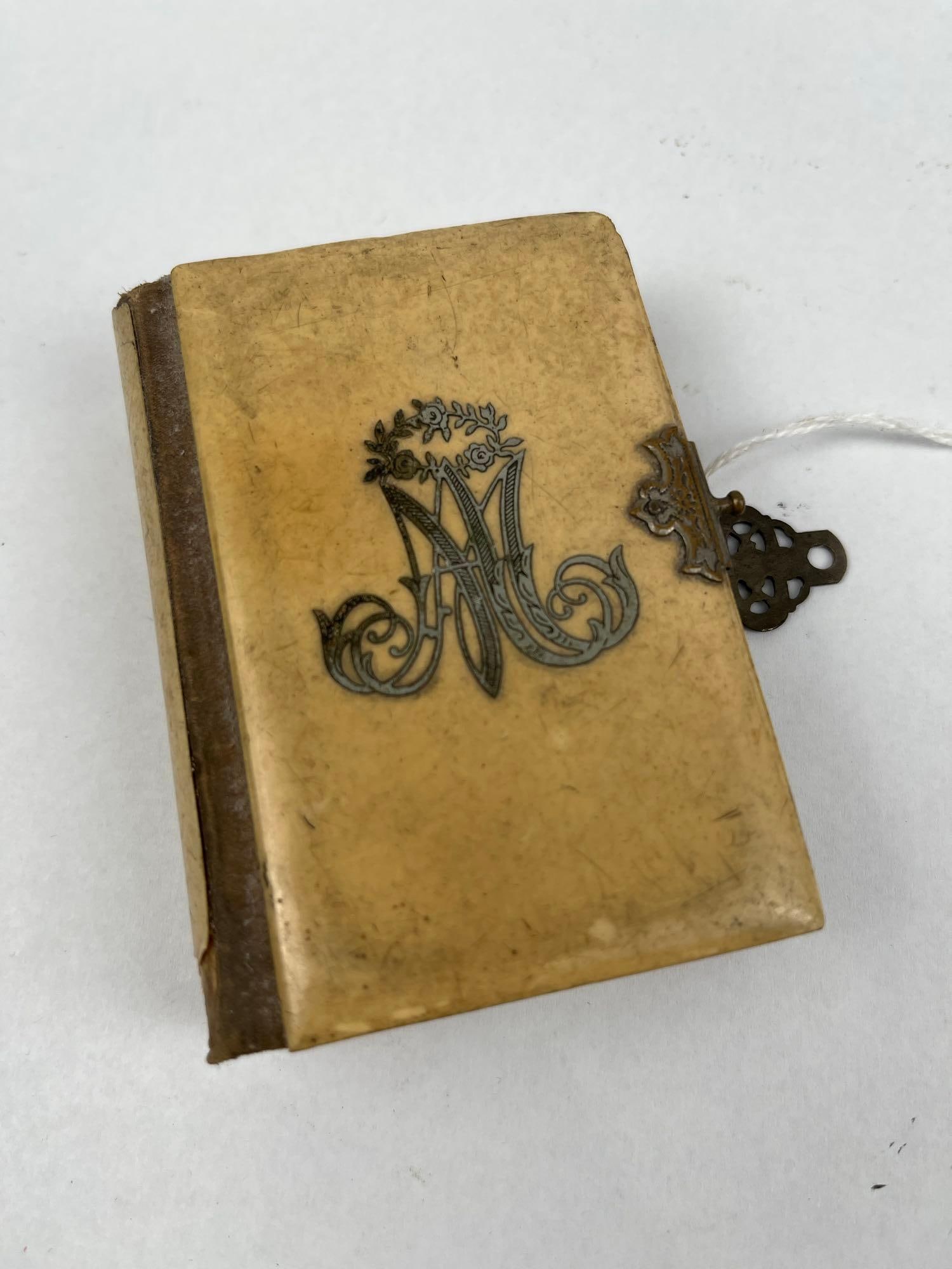 Late 19th C. Celluloid Prayer Book: A miniature Roman Catholic prayer book titled The Pocket Key of Heaven: A Manual of Prayers. The book is bound in cream-coloured celluloid covers with a brown cloth spine. The front cover features an