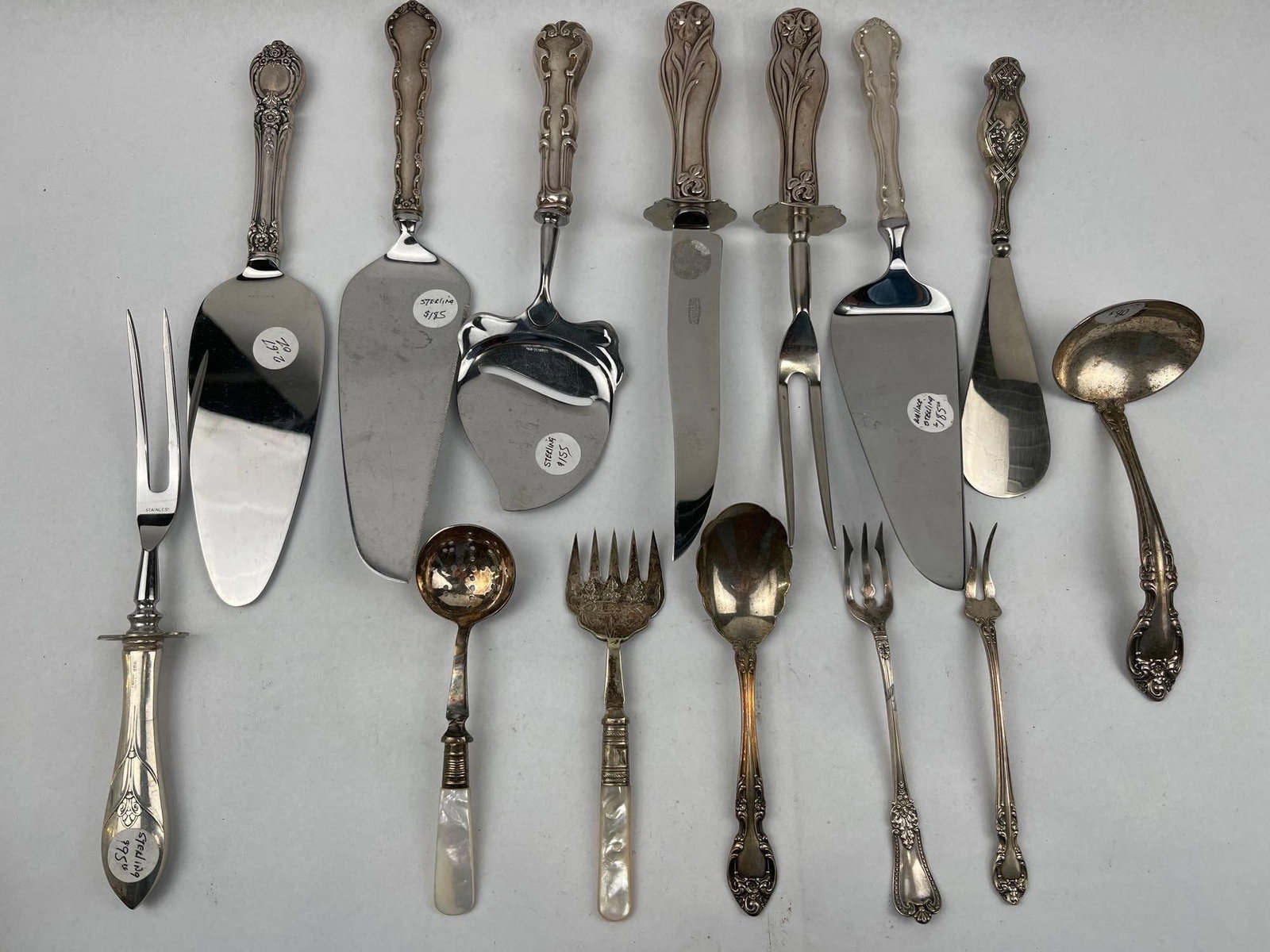 Str. & Silver-Plated Serving Utensils: A collection of various serving utensils including pie servers, a cheese plane, a carving knife and fork set, mother-of-pearl handled serving pieces, a ladle, and an assortment of forks and spoons.