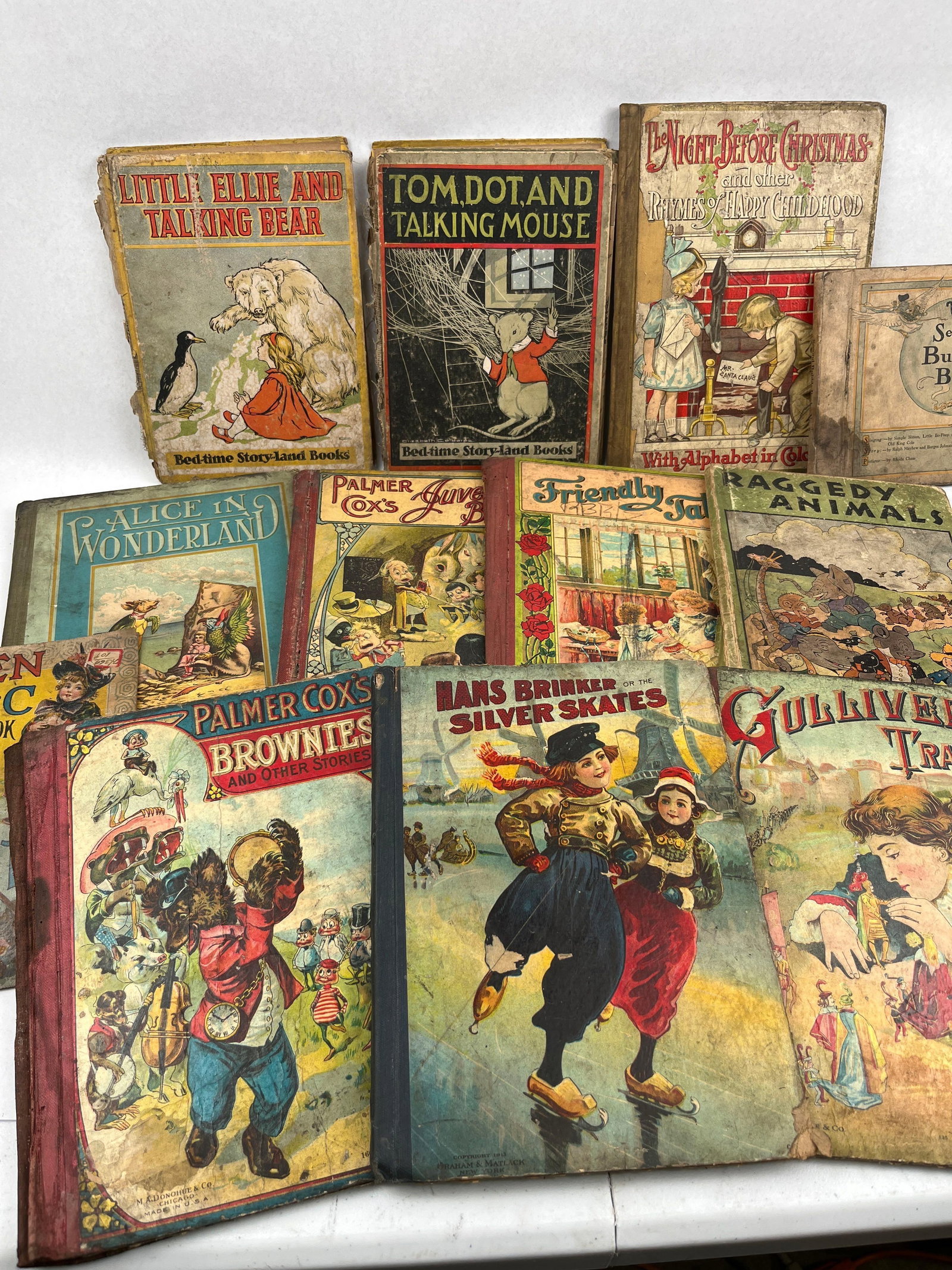 McLoughlin & P. Cox Children's Books: A collection of antique children's books from the late 19th and early 20th centuries, featuring lithographic paper-covered boards. The assortment includes a 1912 edition of "Alice in Wonderland"