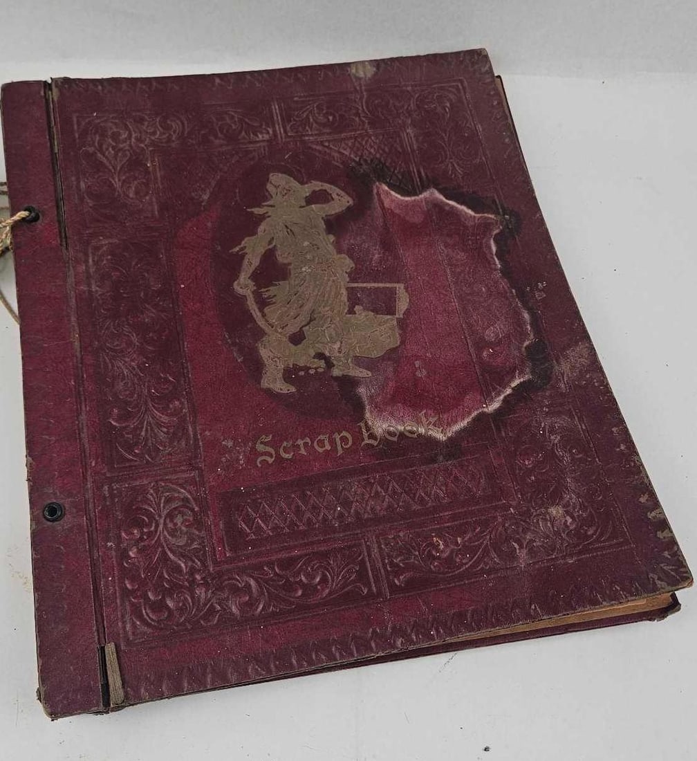 Mid-20th C. Movie Star Pirate Scrapbook: A vintage mid-20th-century scrapbook featuring a dark red embossed cover with a central gold-toned pirate motif and the title Scrap Book in stylized blackletter script. The volume is cord-bound throug