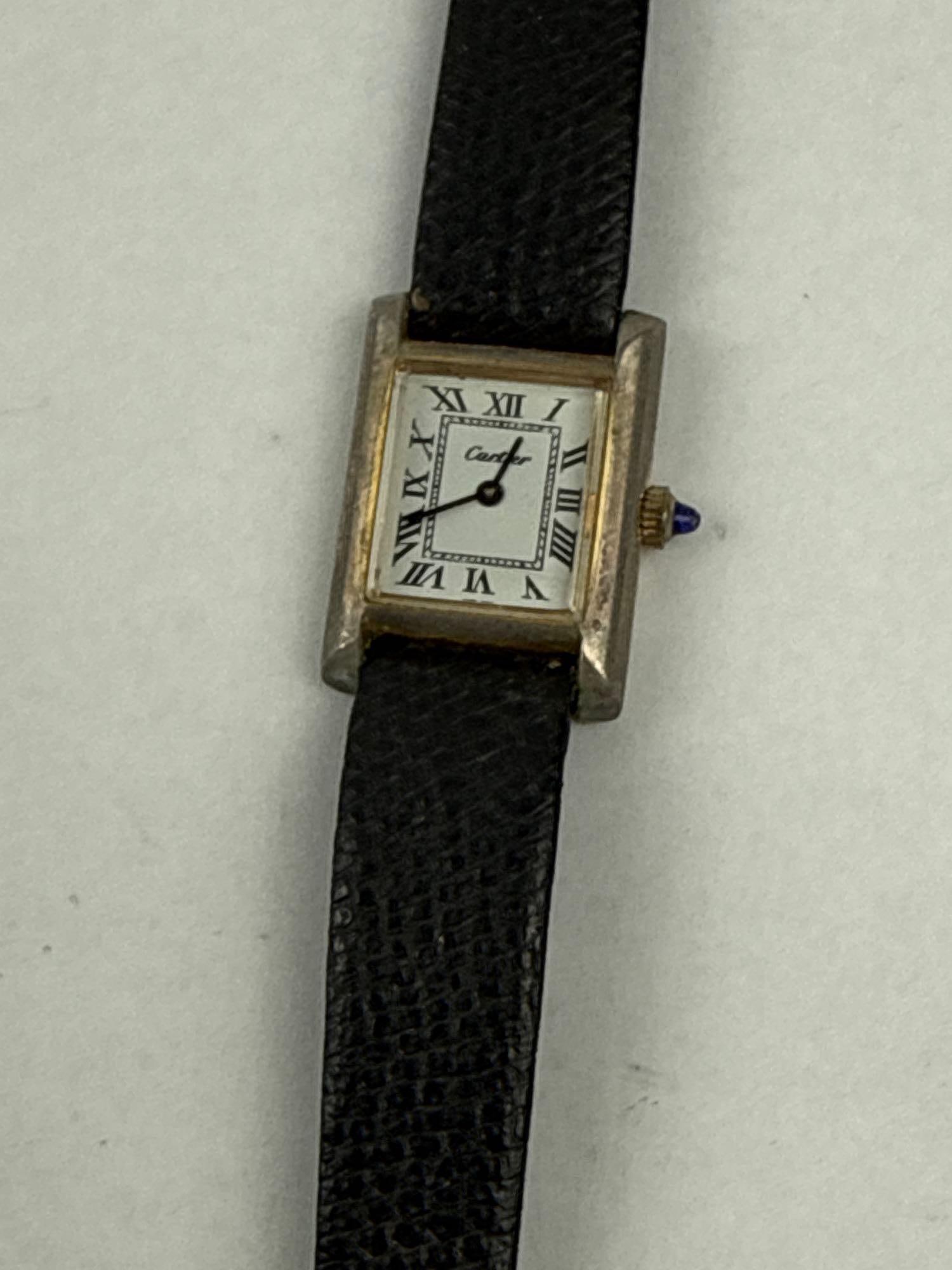 Cartier 18K Gold Electroplated Tank: This vintage rectangular tank-style wristwatch features an 18K gold electroplated case and a manual wind mechanical movement. The white dial is printed with black Roman numeral hour markers, a railtra