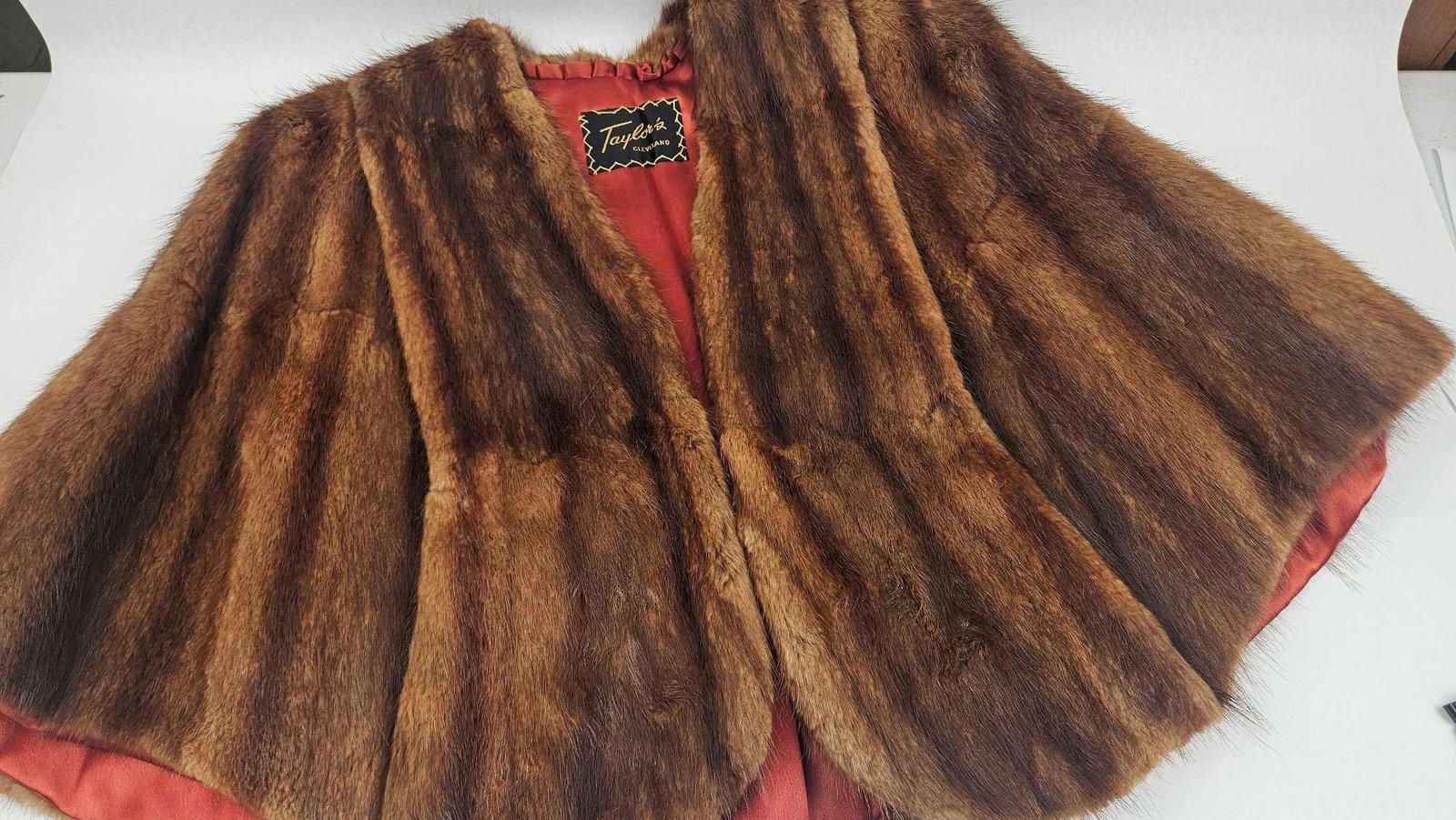 Taylor's Cleveland Mink Fur Cape: A vintage fur cape by Taylor's Cleveland, constructed from mink fur with a vertically-striped pattern in alternating shades of brown and dark amber. The garment features an open-front design with a