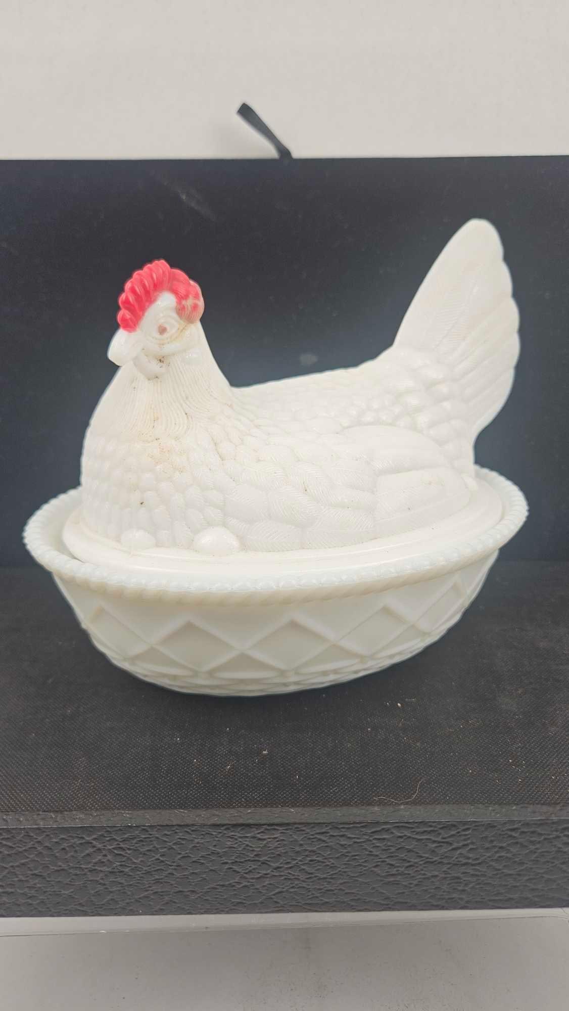 Milk Glass Hen on Nest Covered Dish: This two-piece covered dish is crafted from opaque white milk glass. The lid is molded in the form of a nesting hen featuring a split-tail design, detailed feather texture, and a beaded rim. The comb