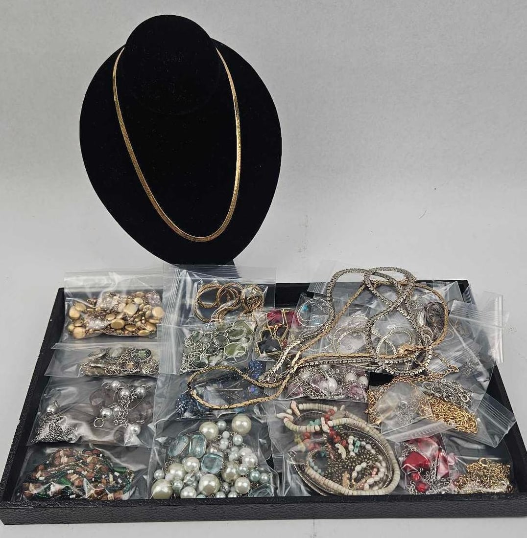 & Costume Jewelry Assortment: A diverse collection of fashion jewelry featuring a variety of styles, materials, and finishes. Included is a prominent gold-tone herringbone flat-link necklace. The remainder of the collection is