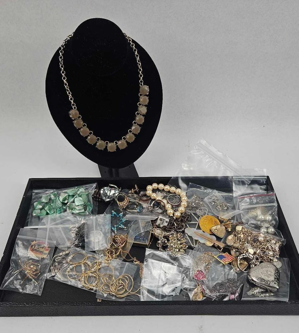 Costume Jewelry, Pins & Accessories: An assortment of costume jewelry and accessories presented in a black tray. The collection features a statement necklace displayed on a black velvet bust, composed of a gold-tone link chain and large 