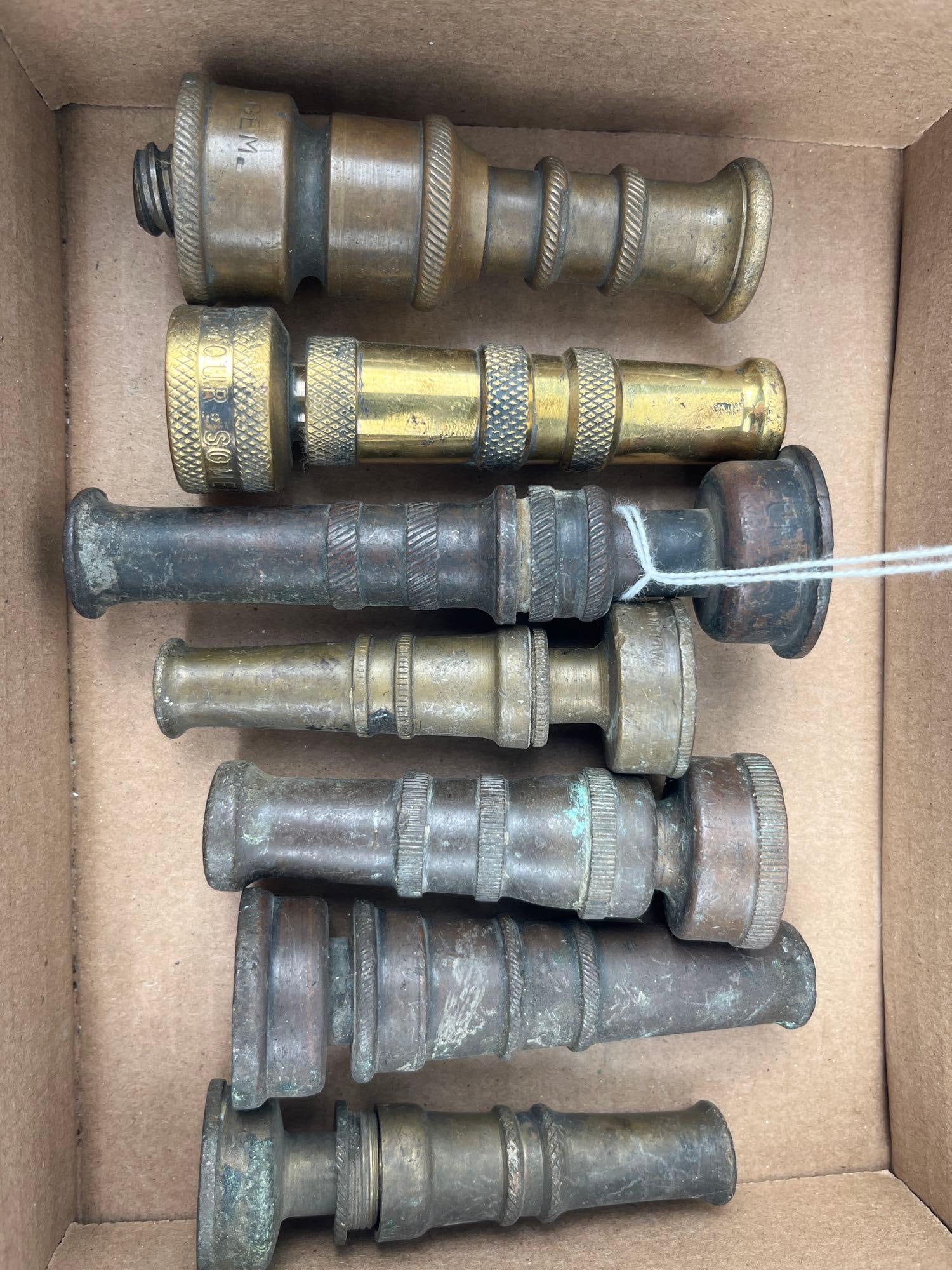 Gilmour & Crane Gem Brass Hose Nozzles: A collection of adjustable twist-spray garden hose nozzles constructed from solid brass and bronze. The group exhibits a variety of industrial forms, featuring knurled adjustment rings, flared spray t
