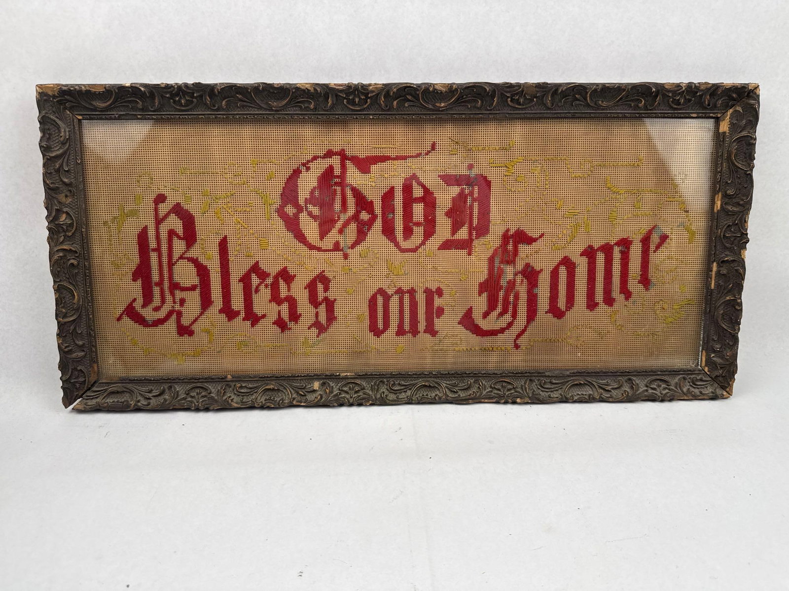Victorian God Bless Our Home Sampler: A late 19th-century Victorian perforated paper needlework motto featuring the religious sentiment God Bless our Home. The text is embroidered in red thread using a Gothic-style script, surrounded by