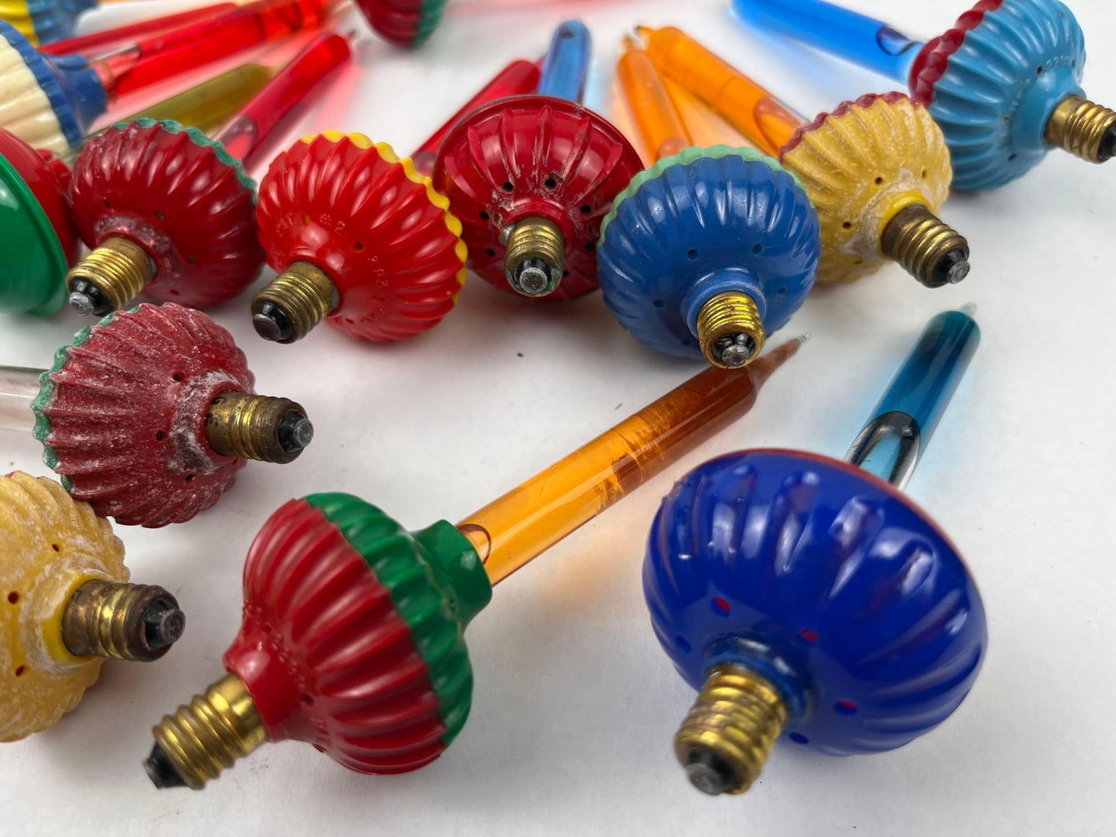 Mid-Century Christmas Bubble Lights: A collection of vintage mid-century Christmas bubble light bulbs. Each bulb consists of a sealed glass tube containing colored liquid, mounted atop a decorative molded plastic base with a metal candel