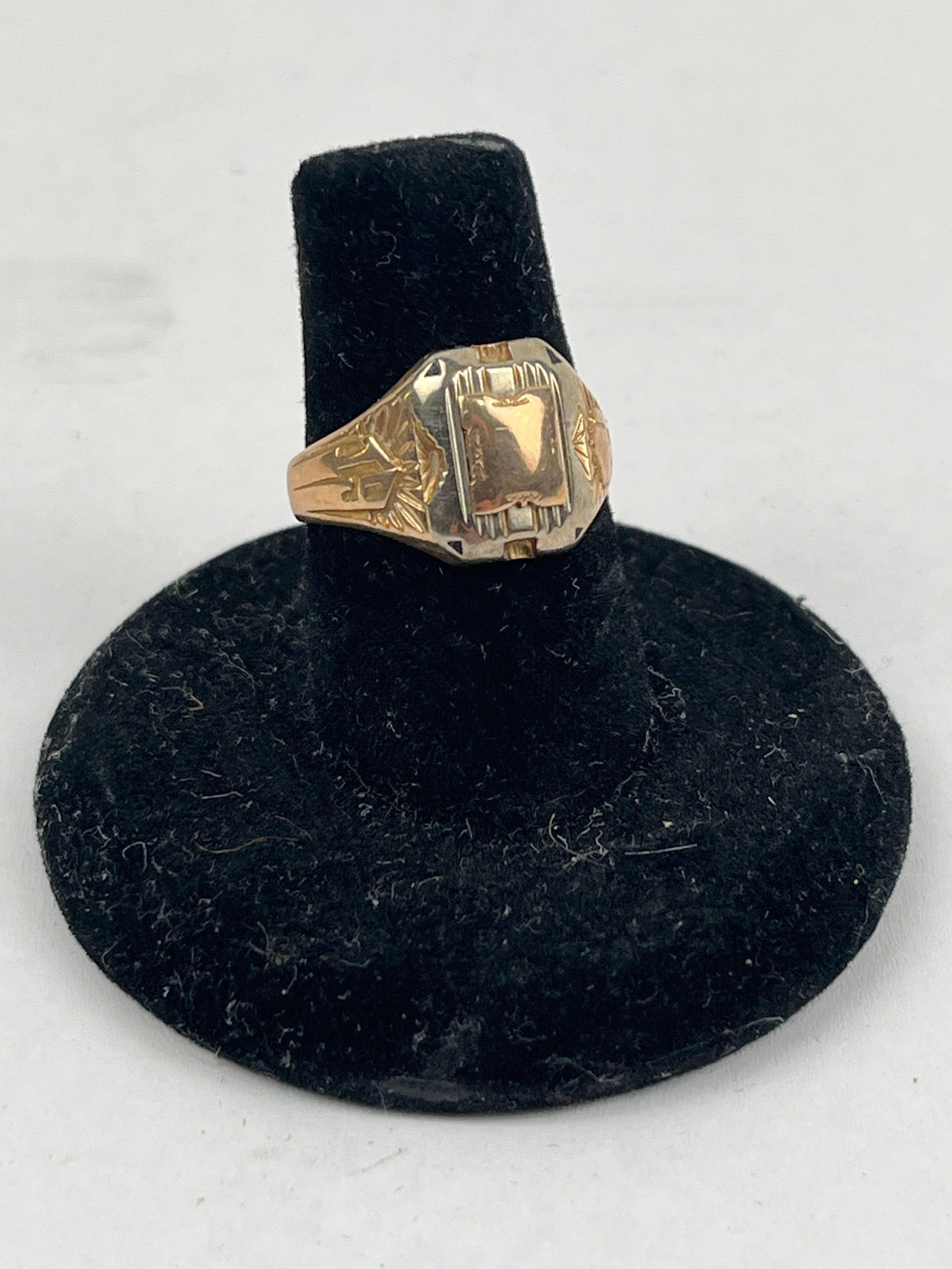 10 Karat Two-Tone Gold Signet Ring: An American signet-style ring constructed from two-tone 10 karat gold. The design features a raised yellow gold rectangular plaque centered on an octagonal white gold face. The shoulders are decorated