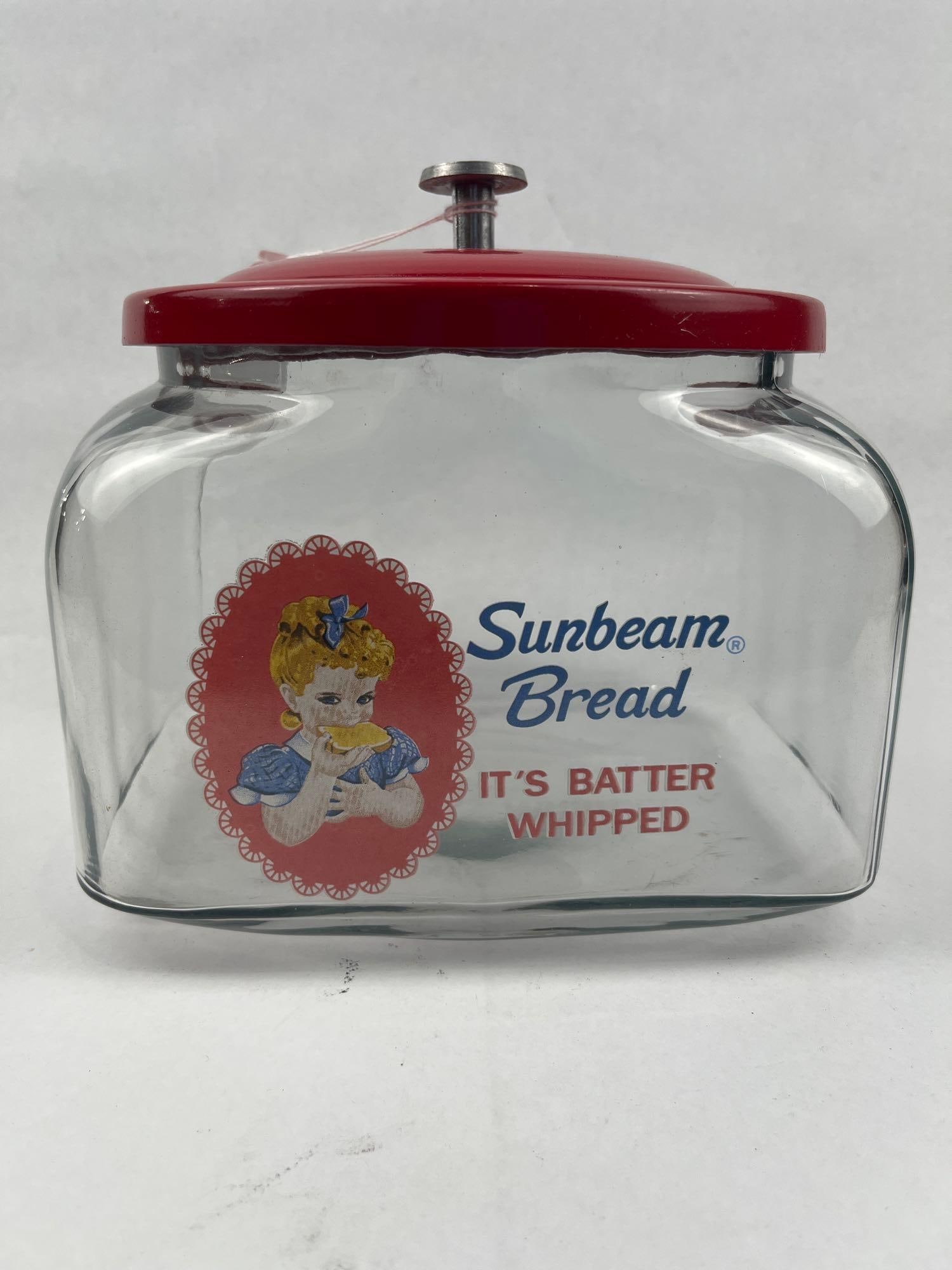 Sunbeam Bread Glass Jar, Red Metal Lid: A vintage advertising counter jar of rectangular form with rounded shoulders, constructed from clear glass. The front of the jar features a multi-colored screen-printed graphic depicting the Little