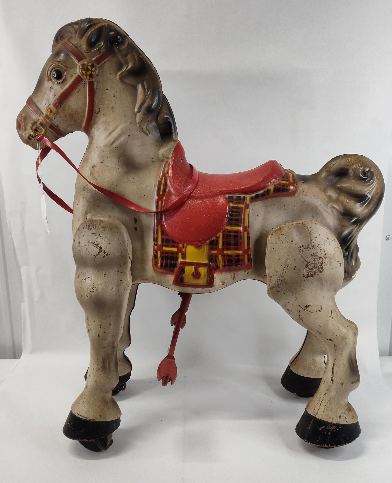 Mobo Bronco Steel Ride On Toy Horse: This ride on mechanical toy horse is constructed from pressed sheet steel with a painted finish. The figure is modeled in a greyish-tan color with dark brown shading applied to the mane, tail, and