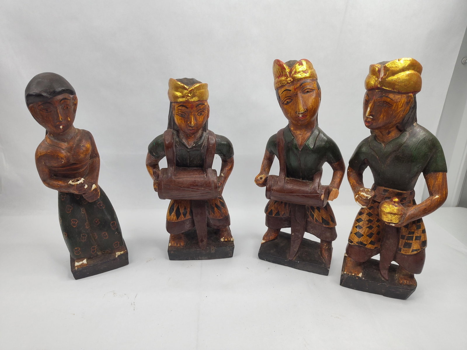 Balinese Carved Wood Musician Figures: A group of hand-carved albesia wood statues featuring three male musicians and one female figure in traditional Balinese attire. The male figures are depicted as performers in a gamelan or beleganjur