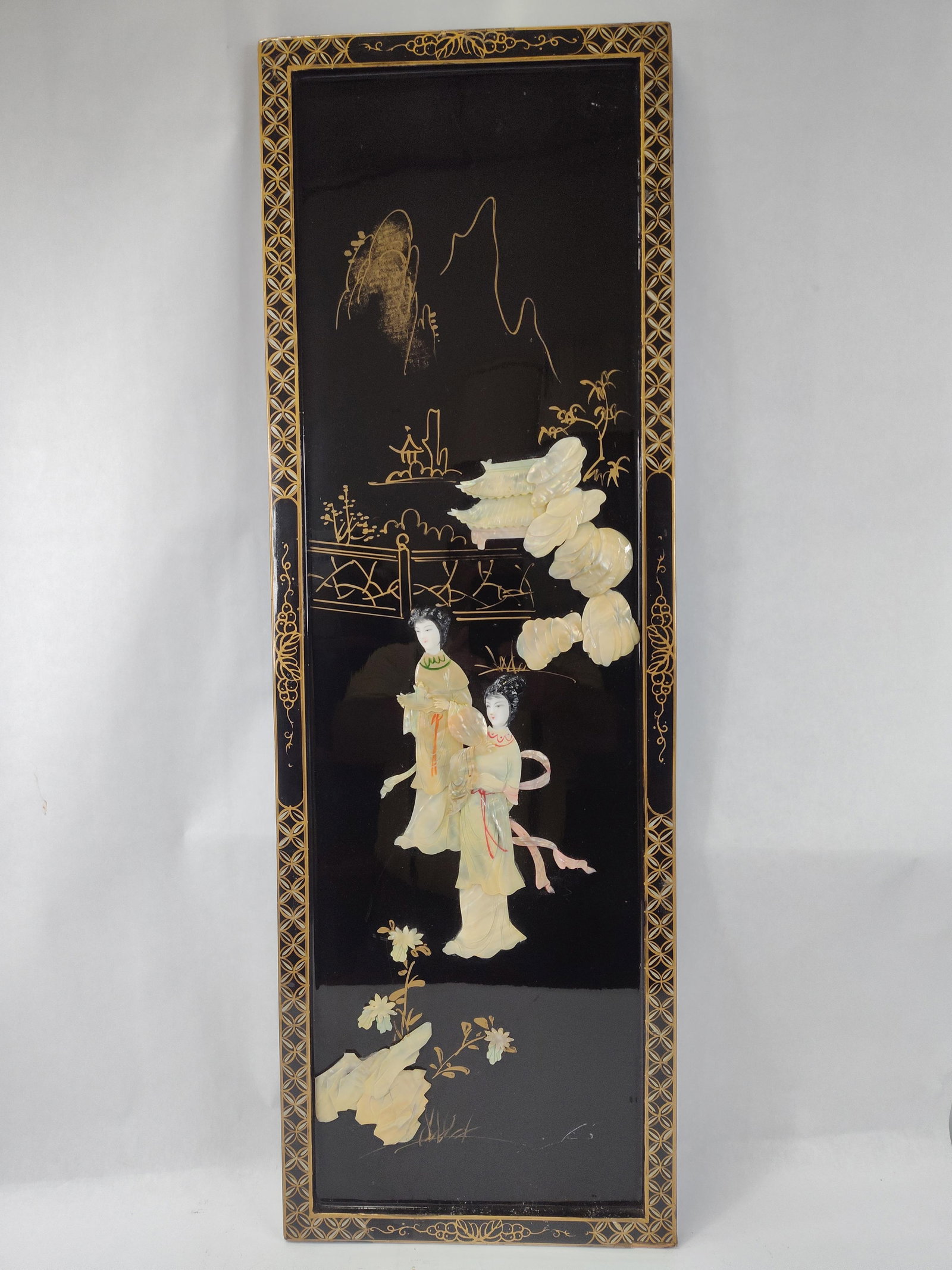 Chinese Lacquer Panel w/ MoP &: A rectangular Chinese wall panel constructed of wood with a black lacquer finish. The central composition features a high-relief scene depicting two female figures dressed in traditional hanfu robes. 