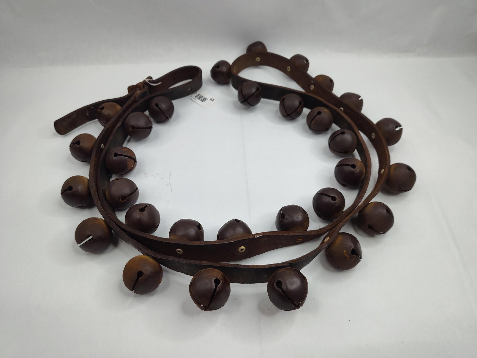 Set Leather Sleigh Straps w/ Brass: This lot comprises a group of leather sleigh bell straps, traditionally used for equine harnesses. The straps are constructed from thick, dark brown harness leather, featuring a variety of spherical