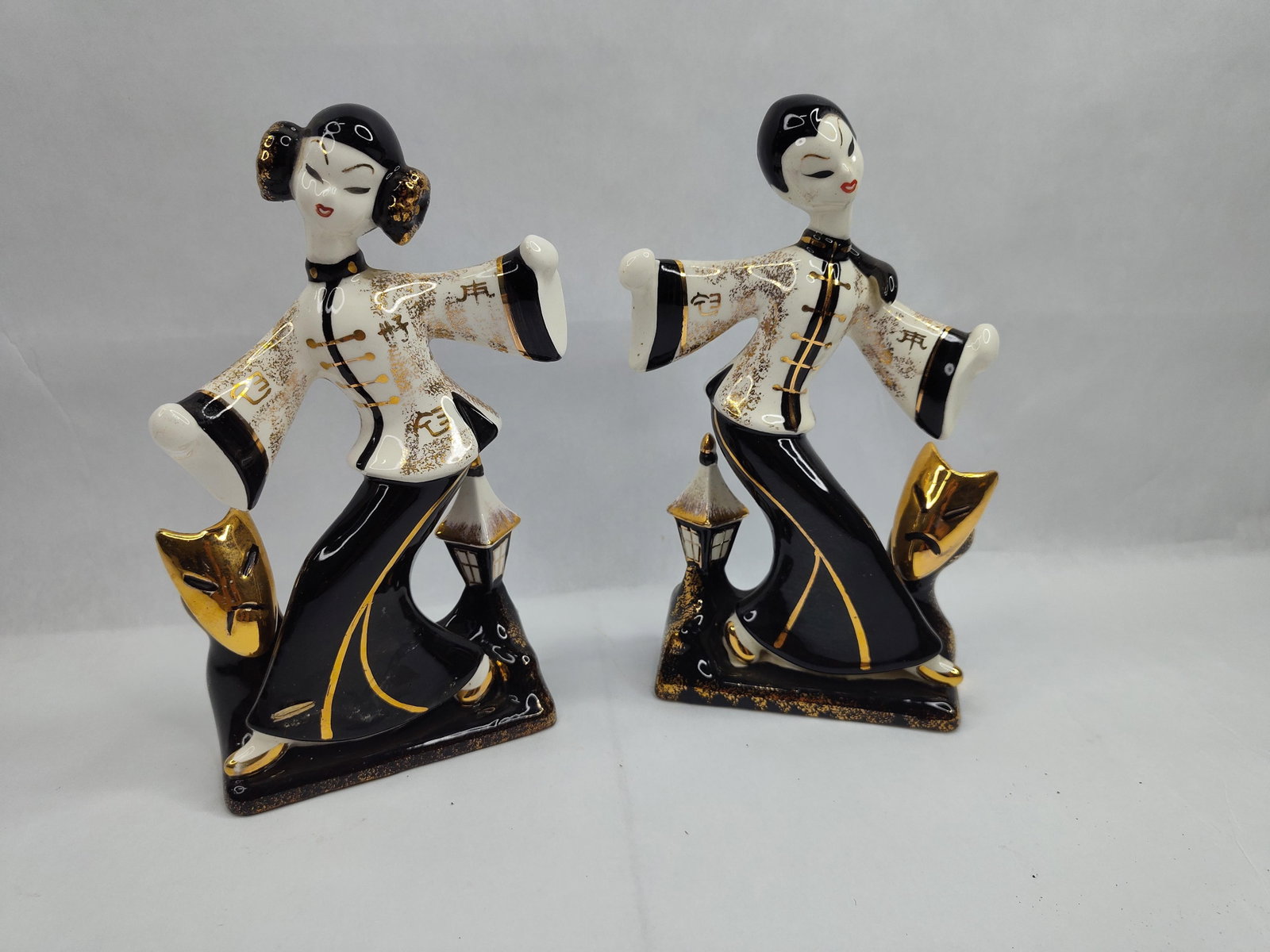 Pair Napco MCM Japanese Ceramic: A pair of Japanese ceramic figurines designed in the mid-century modern aesthetic, depicting stylized figures in theatrical poses. Each figure is constructed with a high-gloss black and white glaze,