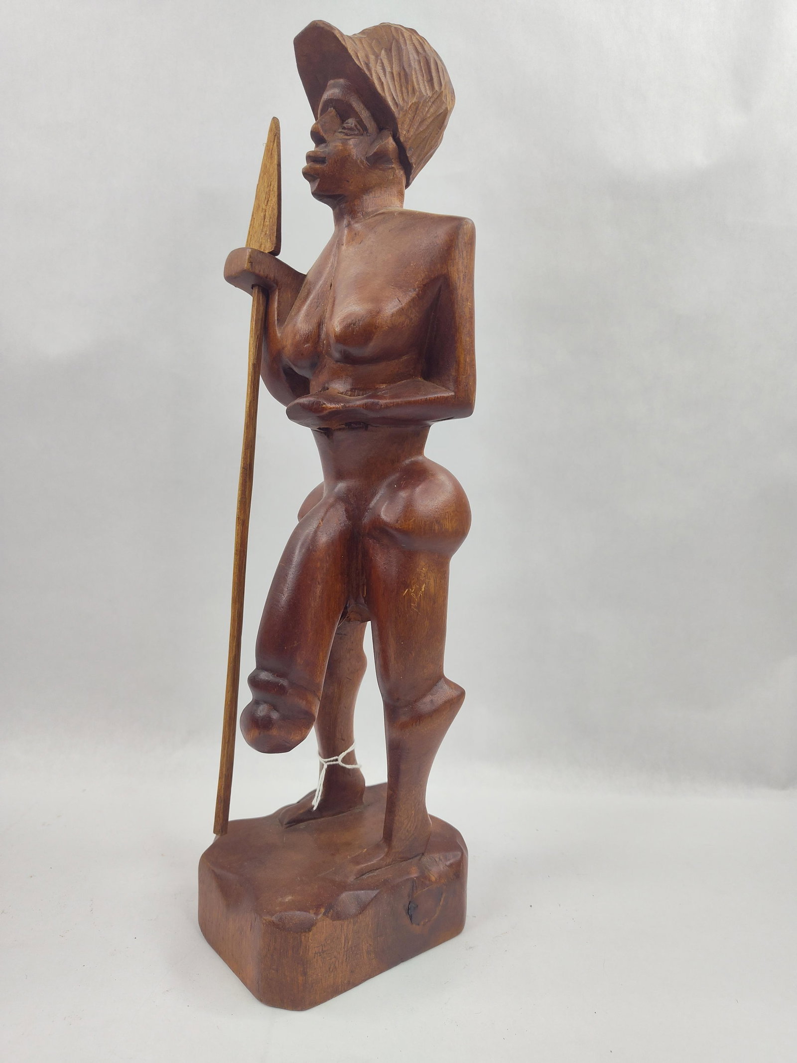 Carved Wood Male Figure w/ Spear: A hand-carved wooden fertility figure depicting a standing male warrior or hunter. The sculpture is fashioned from a single piece of dark-toned hardwood with a polished, semi-gloss finish. The figure