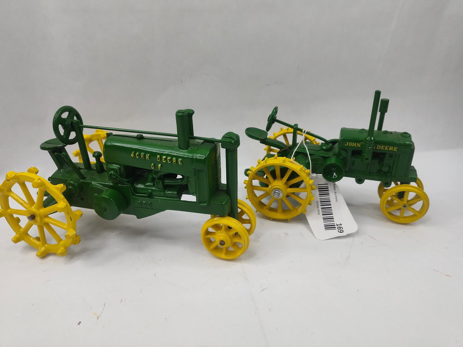 Pair John Deere Die-Cast Model Tractors: Two scale model tractors constructed from die-cast metal, finished in signature green and yellow paint. The first model is a narrow-front tractor featuring yellow steel wheels with lugs. It includes a