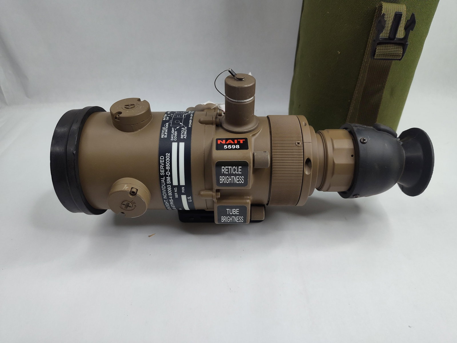 NAIT SU-87/PVS-4 Night Vision Sight: This lot features a tan-colored, individual-served night vision weapon sight and a green canvas carrying case. The sight, identified as a SU-87/PVS-4, is constructed from a matte-finished composite or