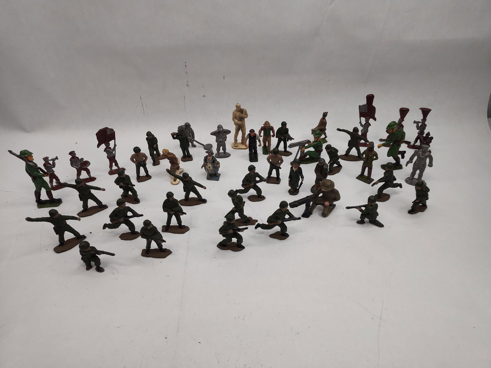 Cast Metal & Composite Figures: A diverse collection of toy figures of various styles and materials, likely dating from the mid-20th century. The group primarily consists of cast metal and composite figures, many of which are