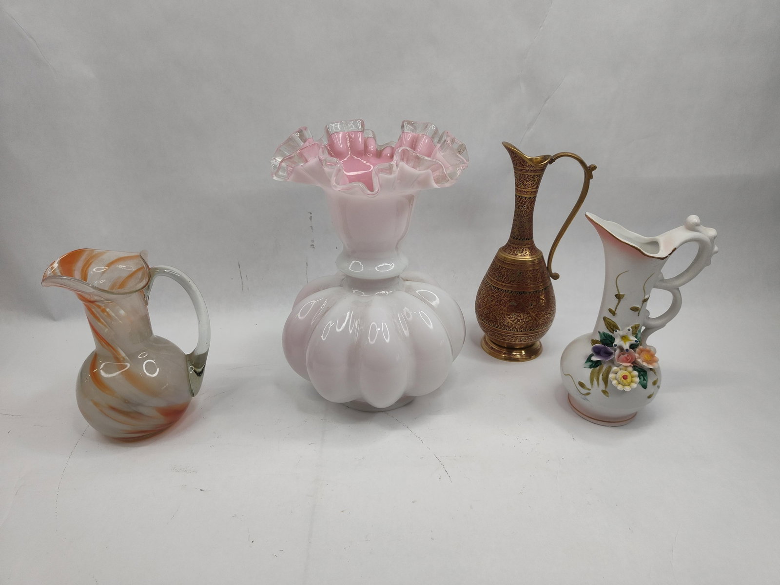 Art & Cased Glass Vases & Pitchers: A collection of decorative objects comprising four distinct pieces of varied materials and styles. Included is a large cased-glass vase featuring a white opalescent melon-form body and a ruffled rim