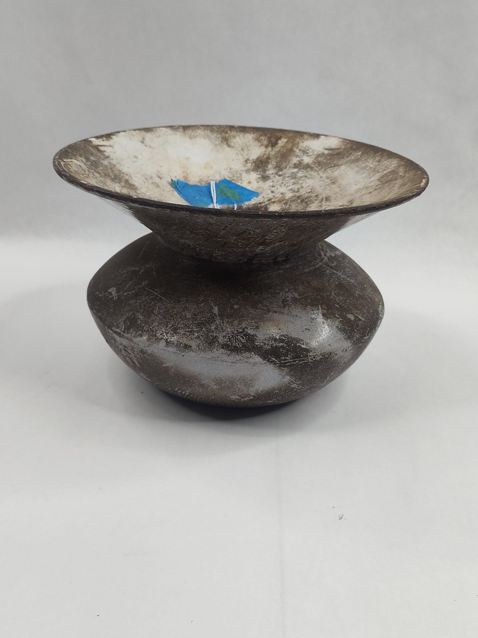 Cast Iron & Porc. Spittoon: A cast iron spittoon or cuspidor featuring a squat, bulbous body and a wide, funnel-shaped flared rim. The exterior of the vessel is composed of cast iron with a dark, oxidized finish. The interior