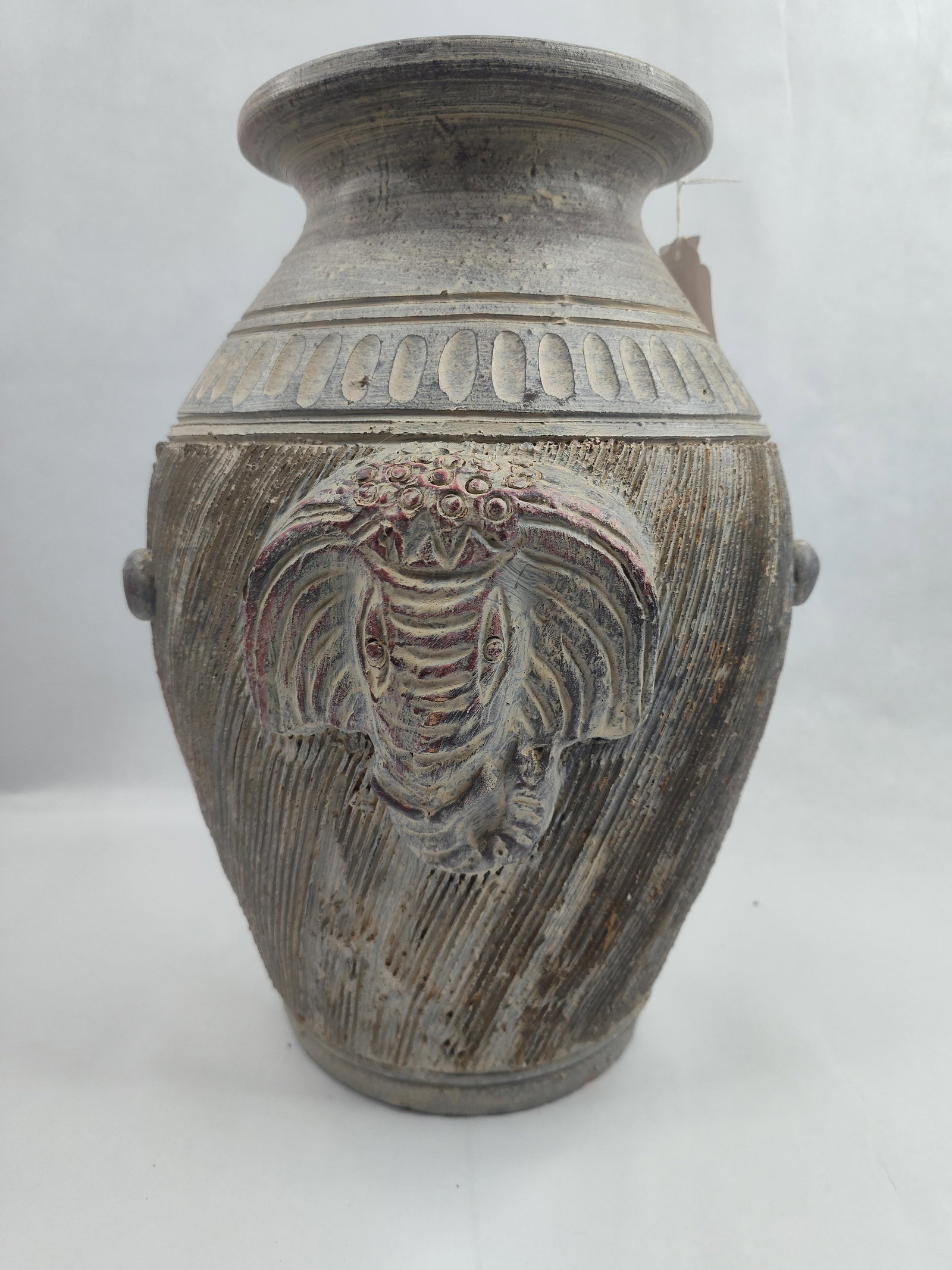 Elephant Motif Earthenware Vase: A wheel-thrown earthenware vase featuring a flared rim, a wide shoulder, and a body that tapers toward a flat, circular base. The vessel is constructed from a reddish-orange clay body, visible on the