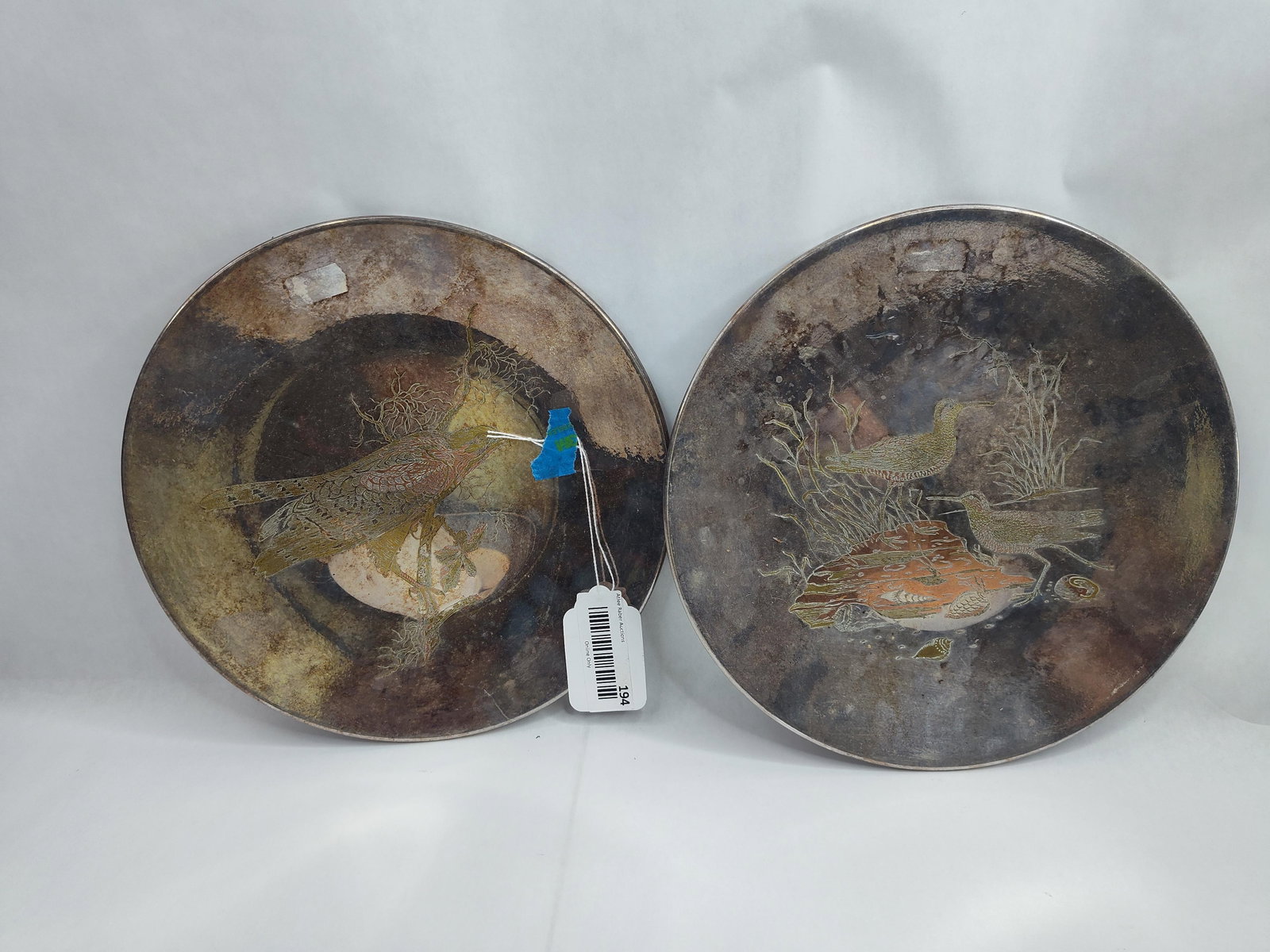 Pair Reed & Barton Audubon Plates: A pair of handcrafted Damascene decorative plates from the Audubon Collection by Reed & Barton. Each plate is constructed of metal with a darkened, patinated surface featuring etched and inlaid