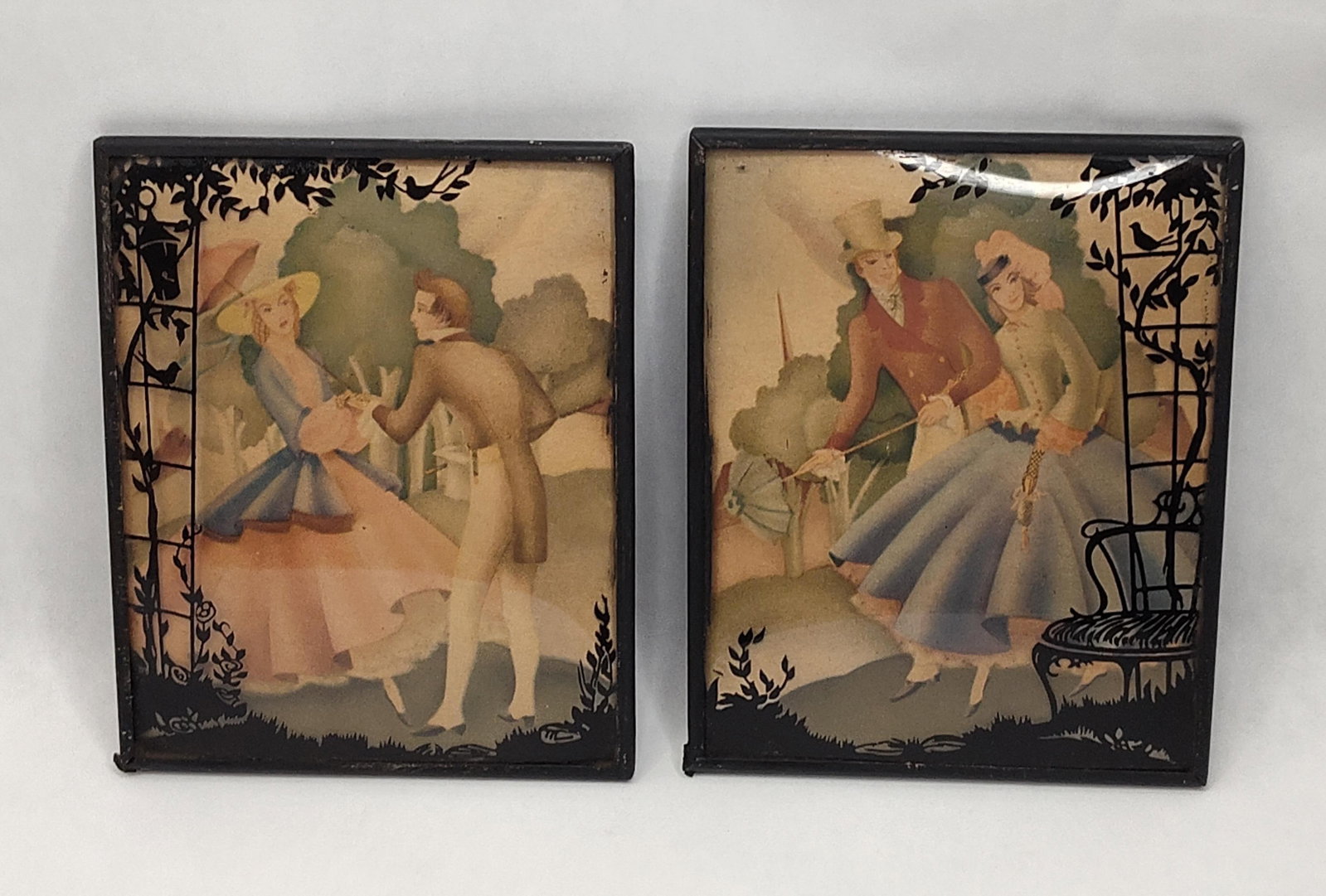 Pair Reverse Painted Glass Pictures: A pair of reverse painted silhouette pictures on convex or "bubble" glass. Each picture features a central scene of a couple in romanticized 19th-century formal attire, including top hats, bonnets,