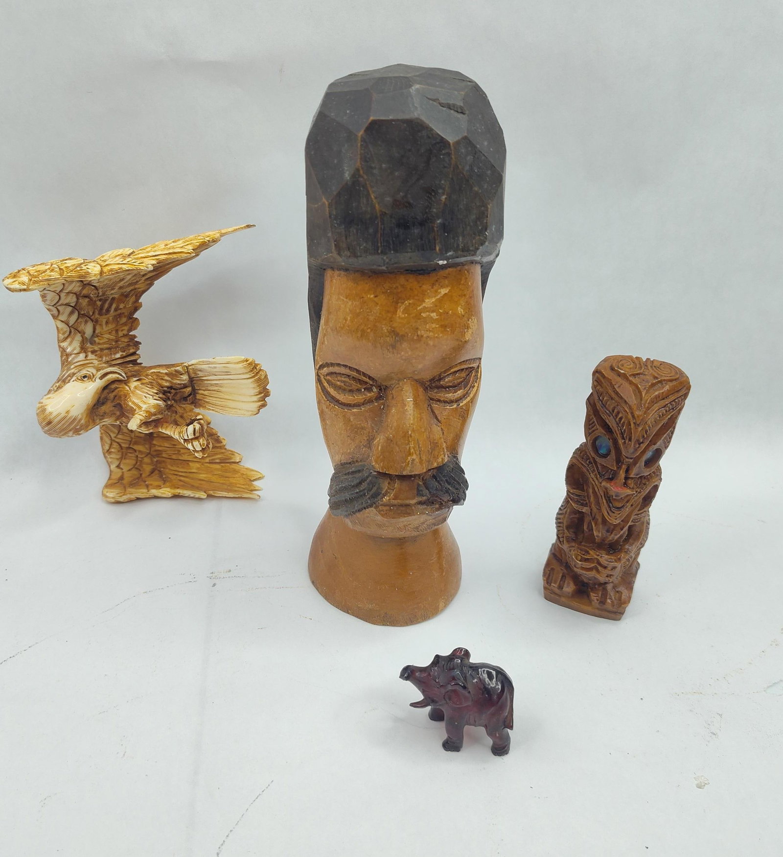 Set Figurative Wood & Resin Sculptures: A group of diverse figurative carvings and sculptures in various materials and styles. The collection includes a large, hand-carved wooden bust of a man featuring a mustache and a faceted headdress