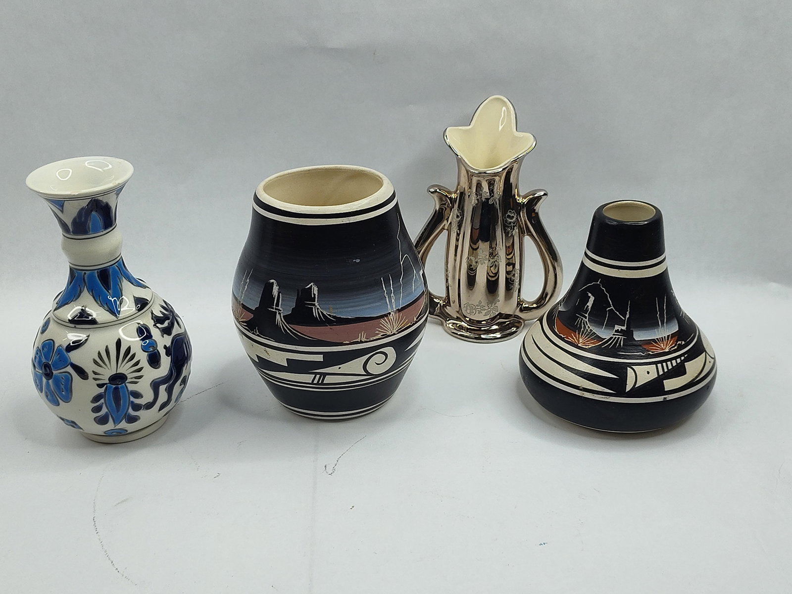 Set of 4 Ceramic Vases & Vessels: This collection consists of an assortment of decorative ceramic vessels featuring varied regional and stylistic influences. A Greek porcelain bud vase features a white glaze decorated with hand-painte