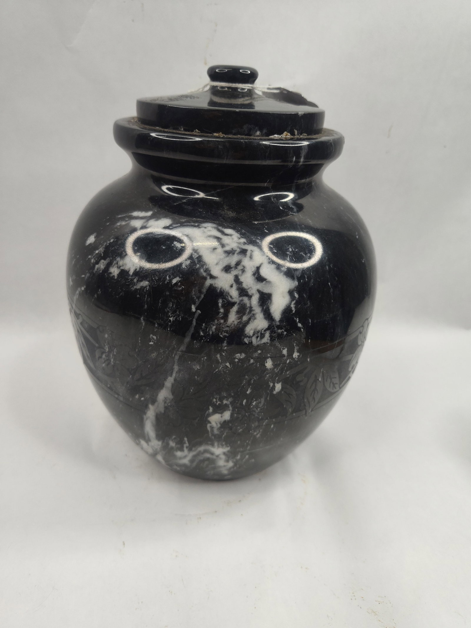 Marble Cremation Urn w/ Floral Band: A cremation urn for adult remains, carved from natural black marble characterized by high-contrast white and grey veining. The vessel is of a traditional bulbous form, tapering to a flat, unpolished c