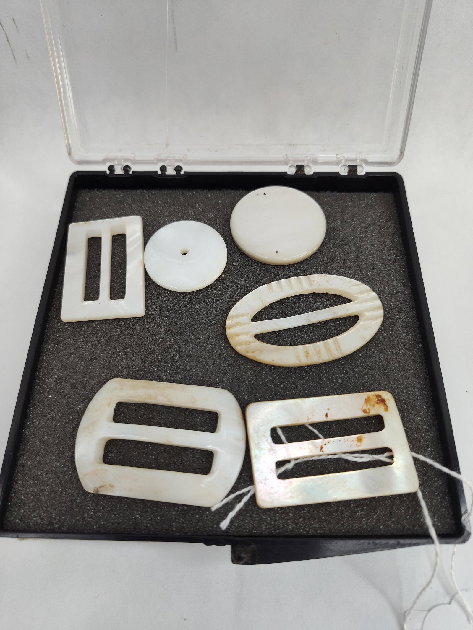 Set Mother-of-Pearl Buckles & Buttons: A collection of mother-of-pearl accessories, likely dating from the 1920s to 1930s based on the characteristic forms of the slides. The group consists of several slide buckles and buttons, including