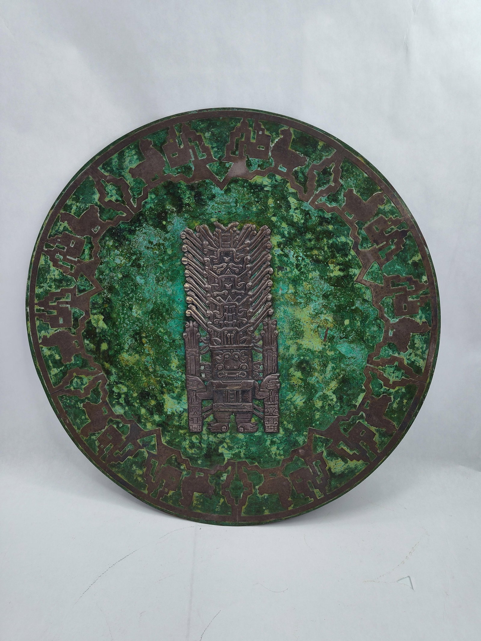 Peruvian Mixed Metal Wall Plaque: A large circular wall plaque constructed from copper and brass, featuring repousse and applied relief iconography inspired by Pre-Columbian Peruvian cultures. The central composition features a