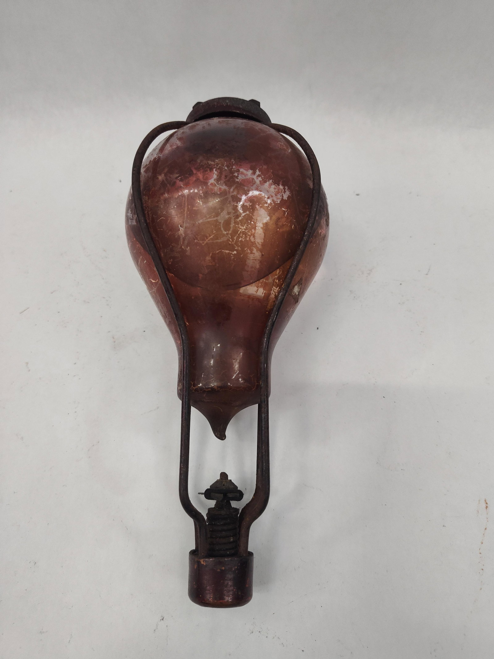 Red Comet Auto Fire Extinguisher: A American fire safety device comprising a glass globe fire grenade and an integrated mechanical deployment system. The glass vessel is a bulbous flask tapering to a point at the base, featuring a