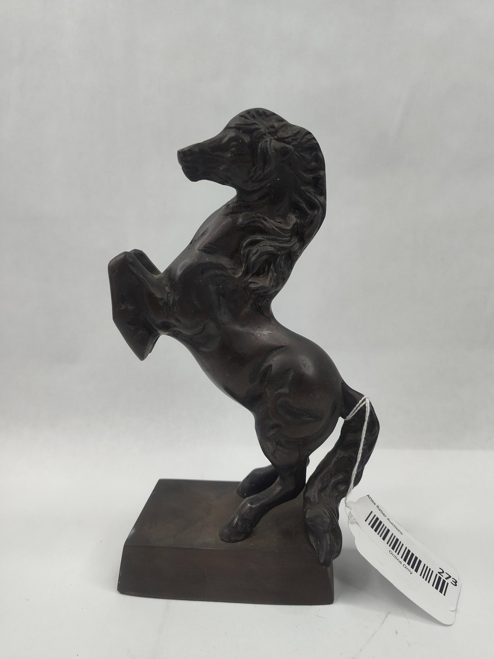 Patinated Bronze Rearing Horse: A dark brown patinated bronze sculpture of a rearing horse, featuring a stylized and spirited pose with a flowing mane and tail. The figure is cast with textured modeling that emphasizes movement over