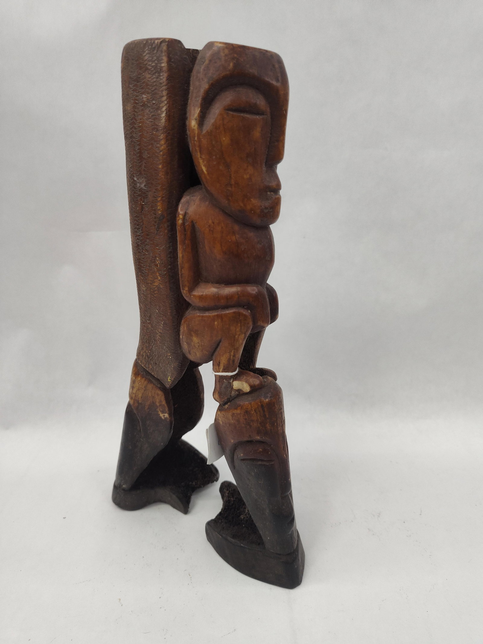 3 Hand-Carved Wood Totemic Figures: This hand-carved wooden sculptural group consists of three anthropomorphic figures integrated into a single vertical composition. The central element features a crouching figure with a large, elongate