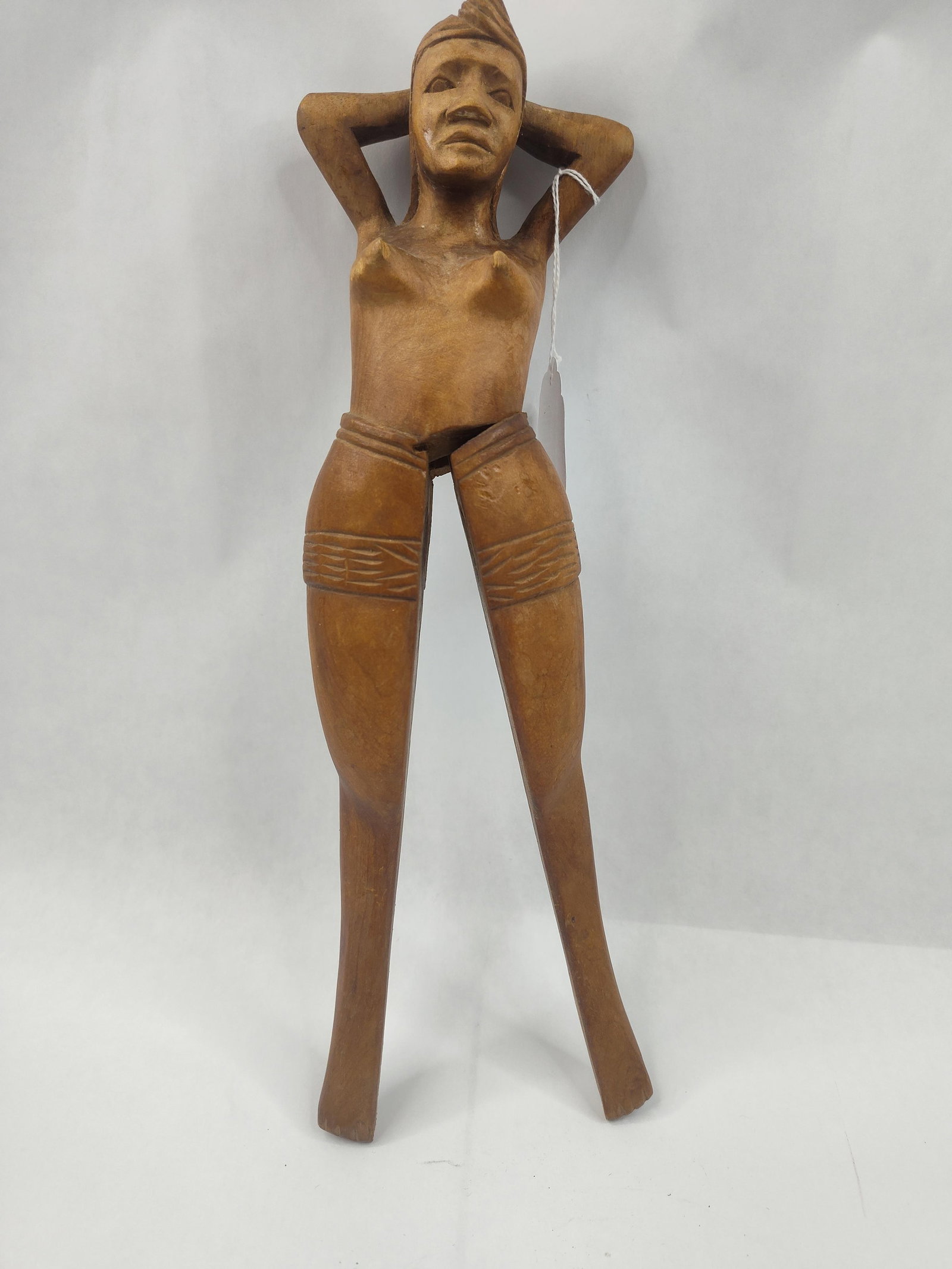 Carved Wood Figural Female Nutcracker: A carved wooden nutcracker fashioned in the form of a standing nude female figure with arms raised behind her head. The object is constructed from a medium-toned wood with a polished finish and