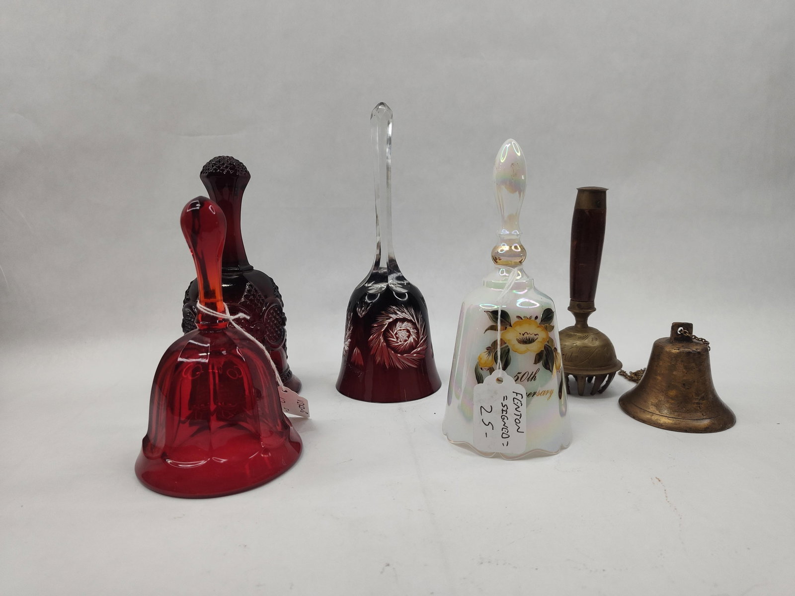 Fenton & Viking Glass & Metal Bells: A collection of decorative bells featuring various materials including hand-painted art glass, cased and cut glass, molded glass, and brass. The grouping includes an iridescent white glass bell with