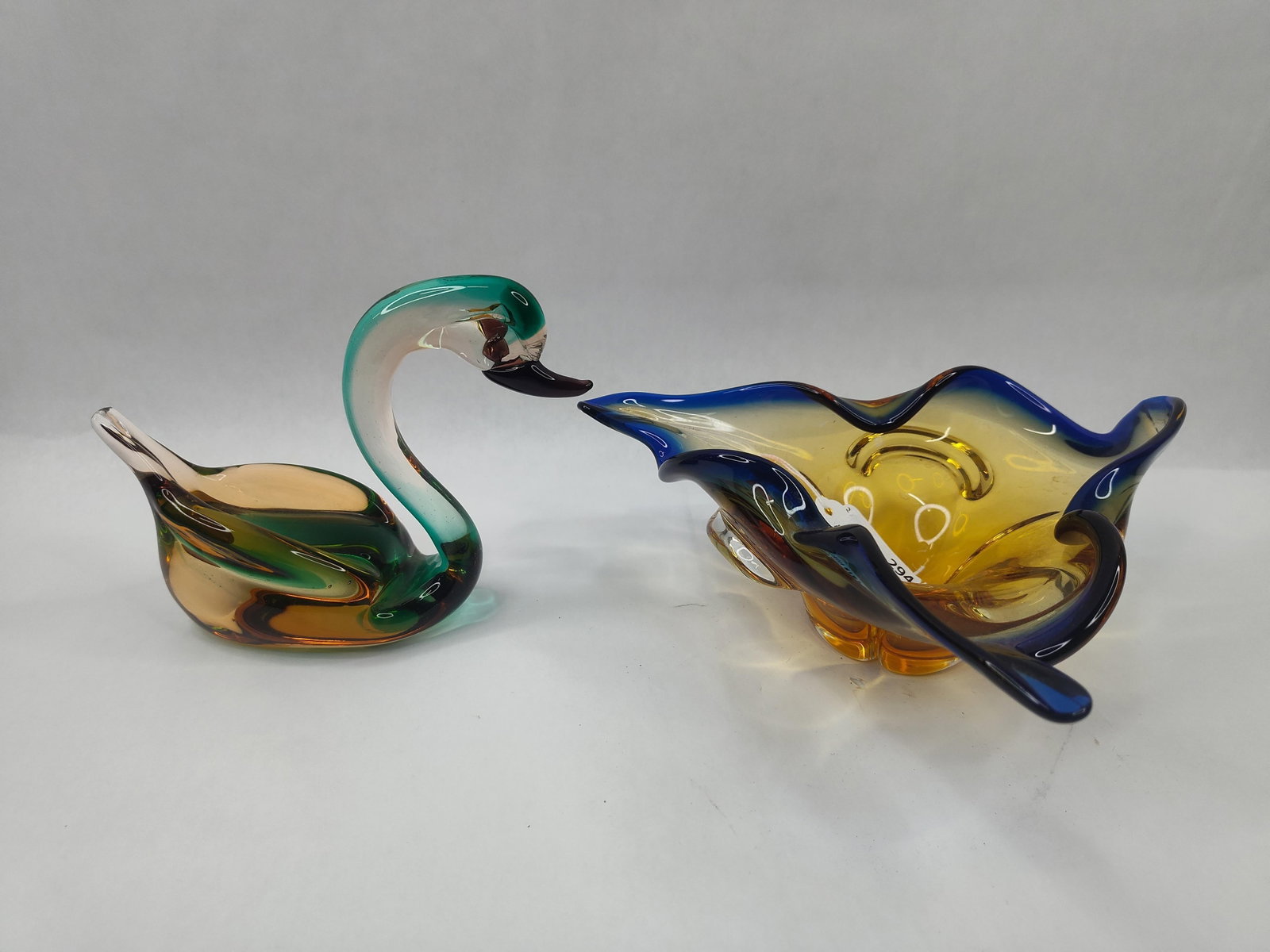 Two Murano Art Glass Tableware Pieces: This lot consists of an Italian art glass swan figurine and a tricorn-style bowl, both featuring the sommerso technique where layers of colored glass are encased in clear glass. The swan is an